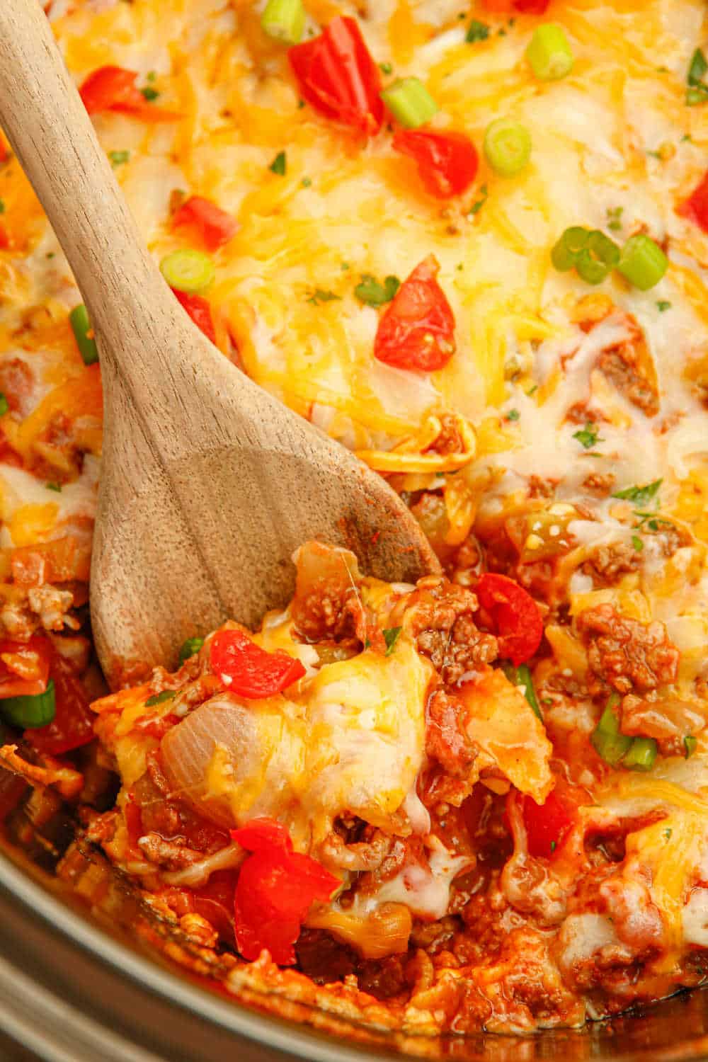 A serving spoon in a crockpot of beef enchilada casserole.