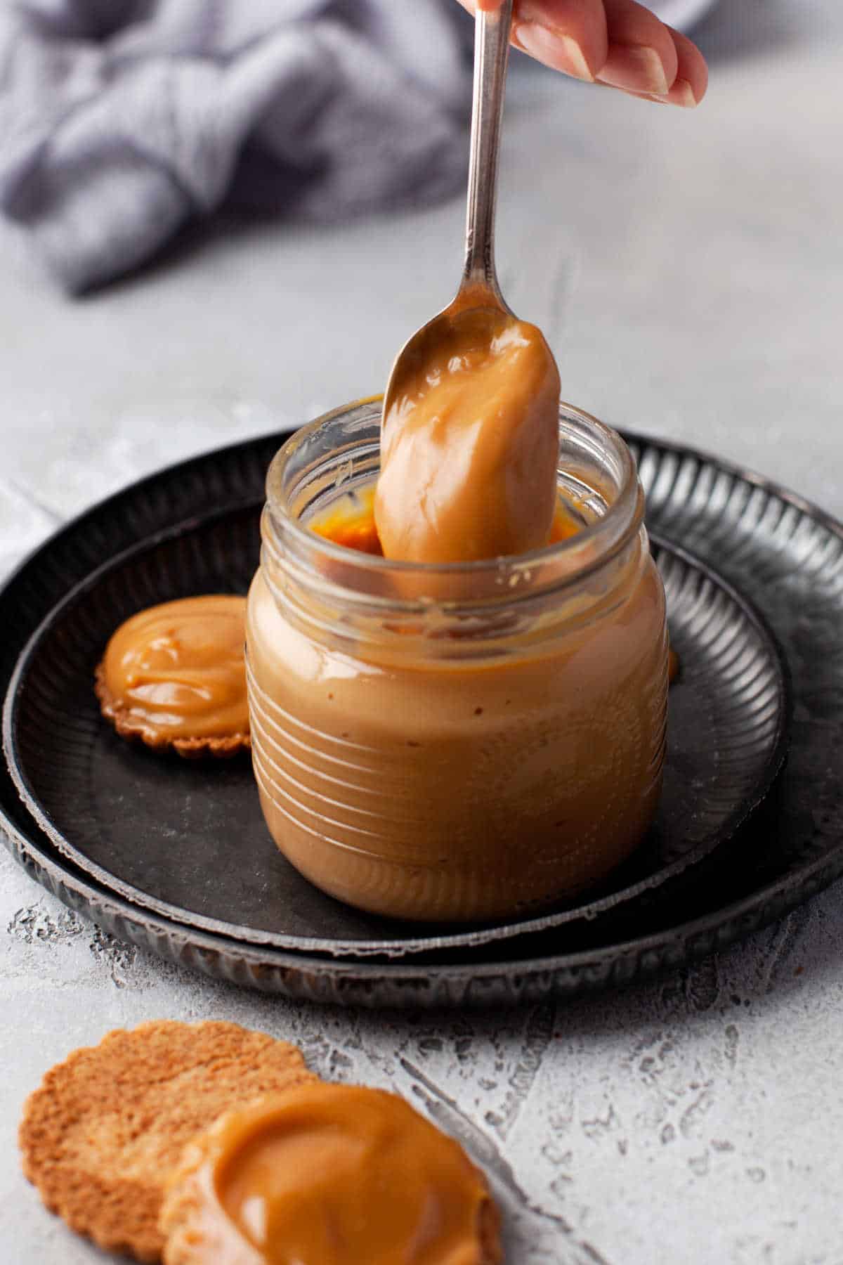 A spoon coming out of a jar of dulce de leche.