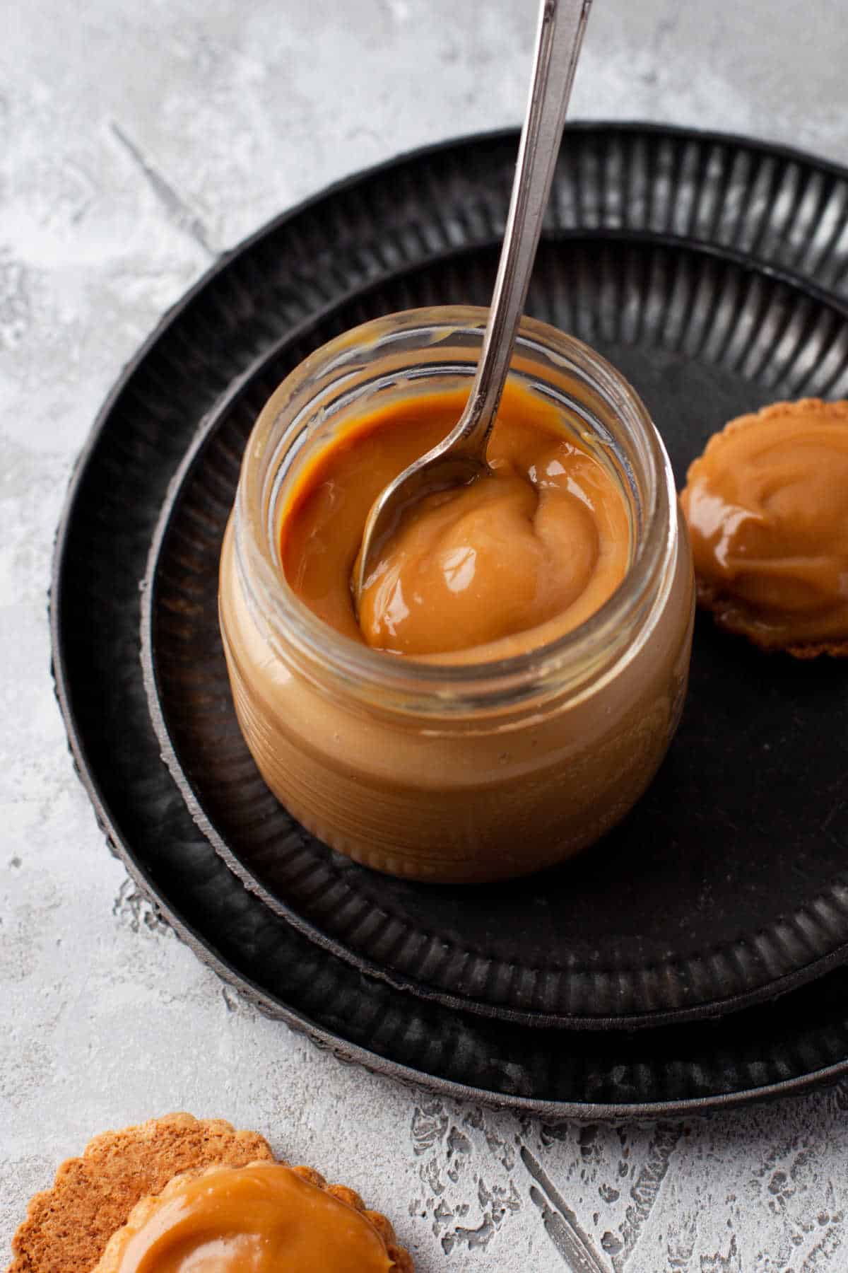 A jar of dulce de leche with a spoon in it.