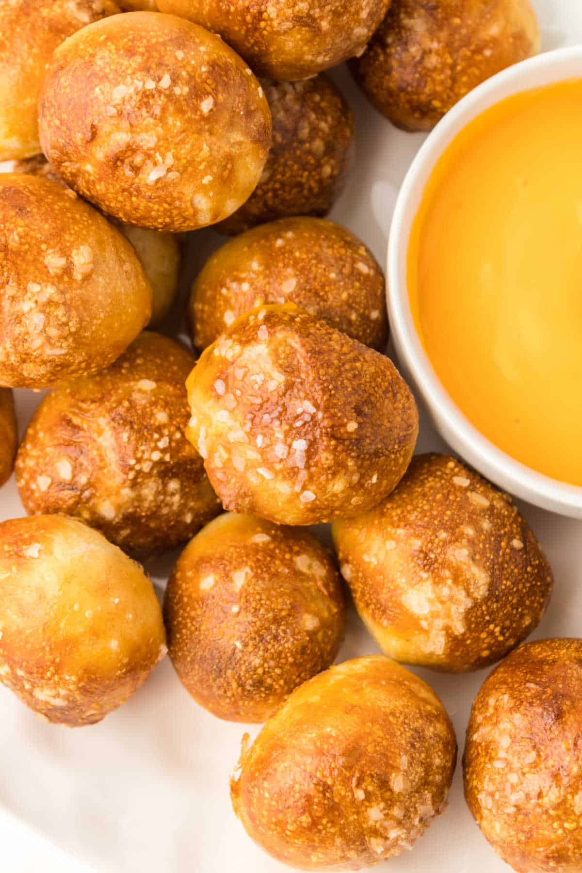 Air fryer pretzel bites on a plate with cheese sauce.