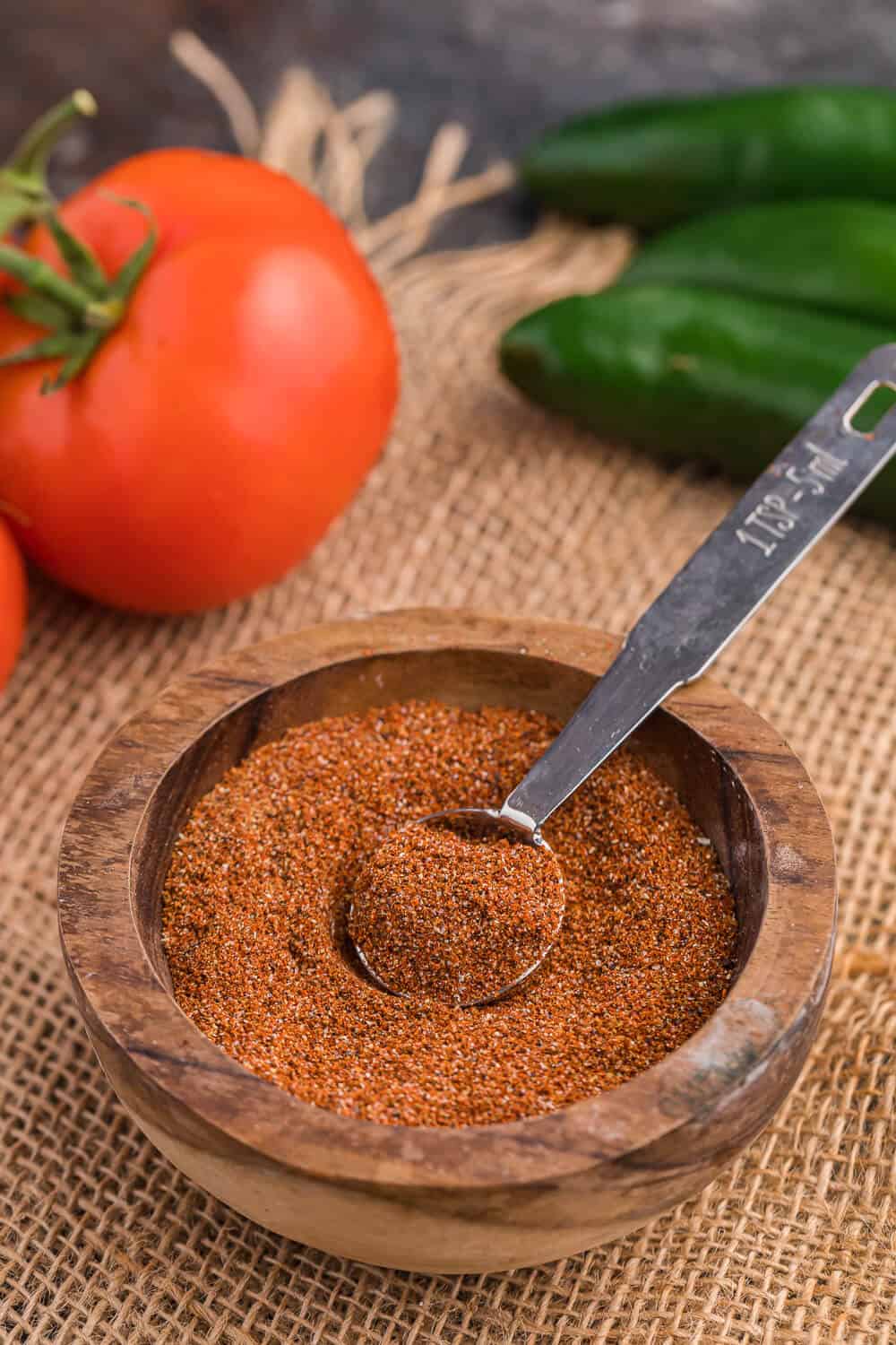 A wooden bowl with taco seasoning and a measuring spoon.