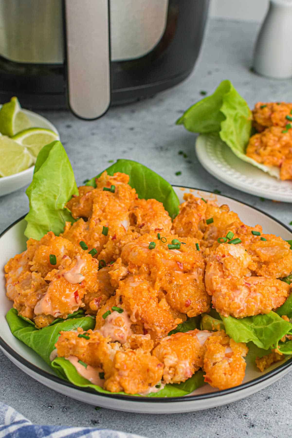 A plate of bang bang shrimp on a bed of lettuce.