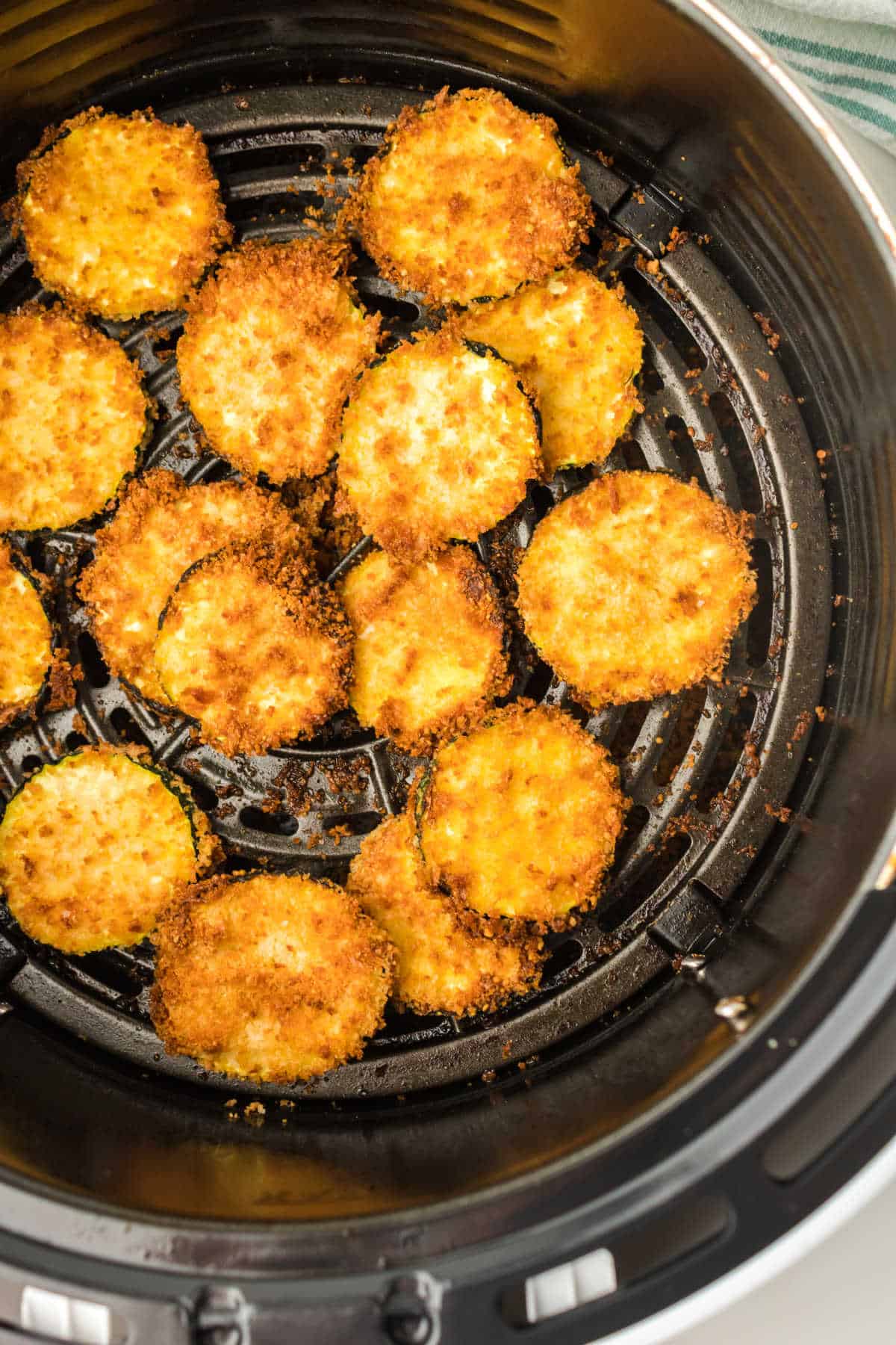 Air fryer zucchini chips in an air fryer basket.