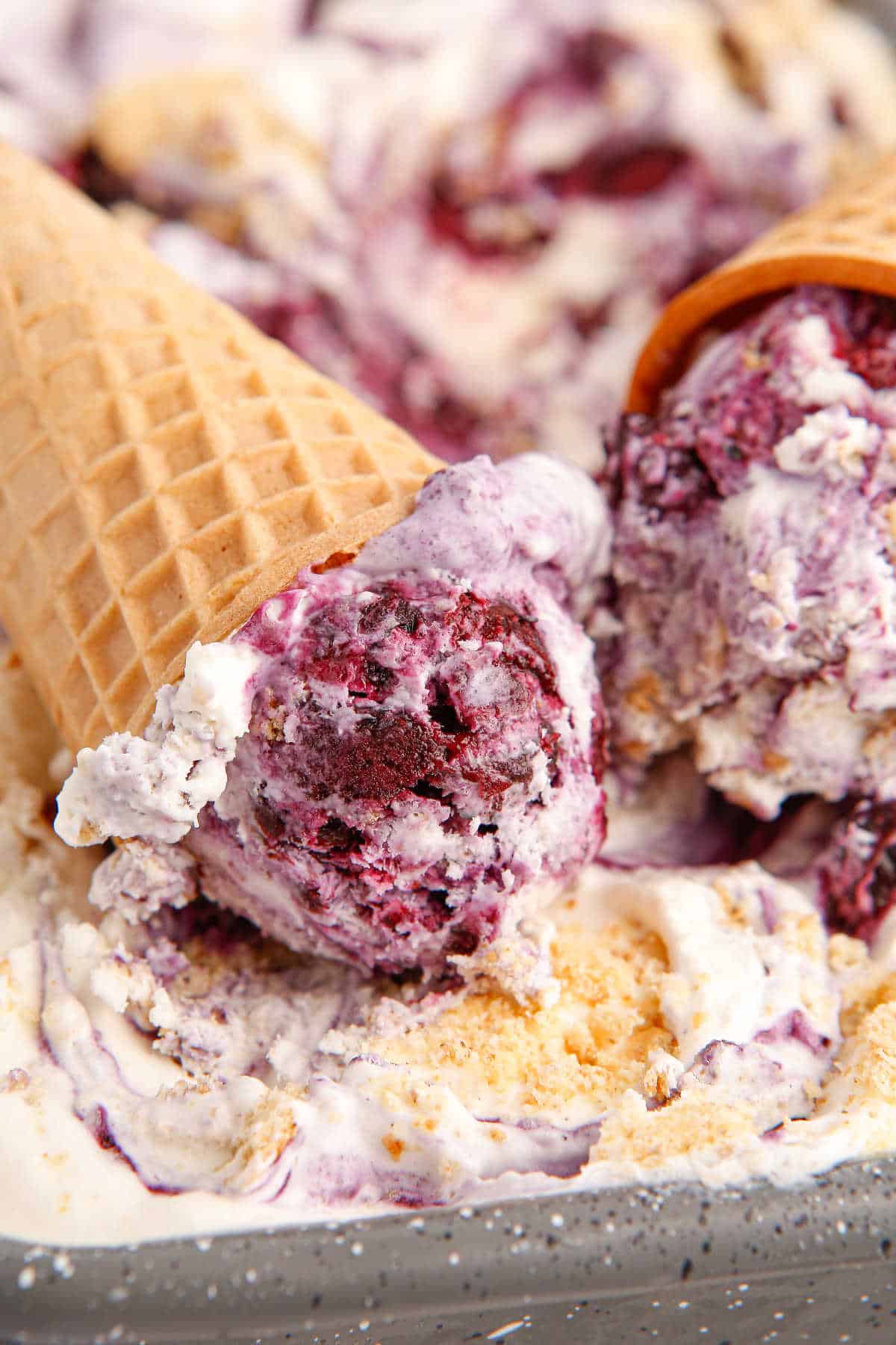 Blueberry pie ice cream cones in a tub of ice cream.