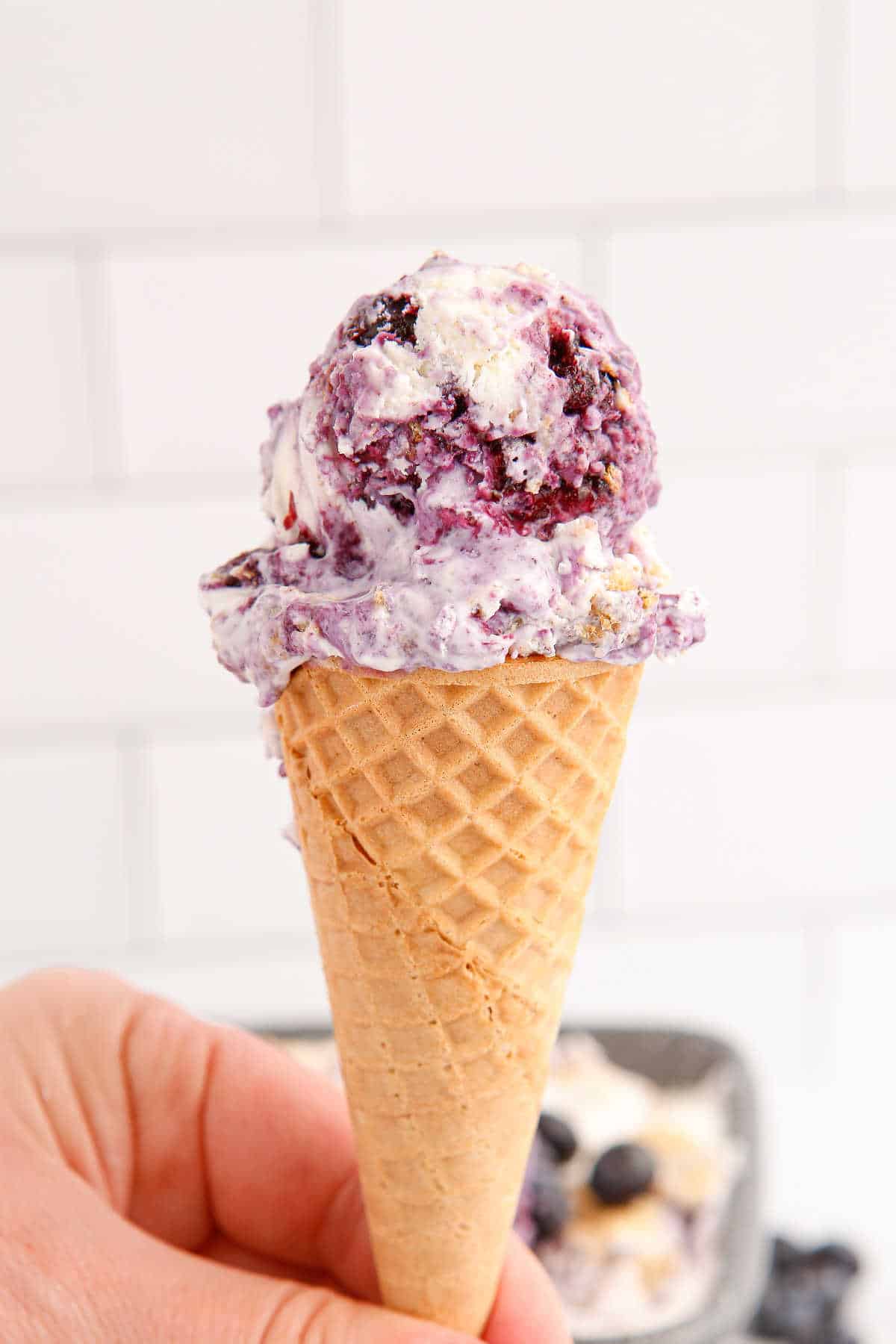 An ice cream cone with blueberry pie ice cream.