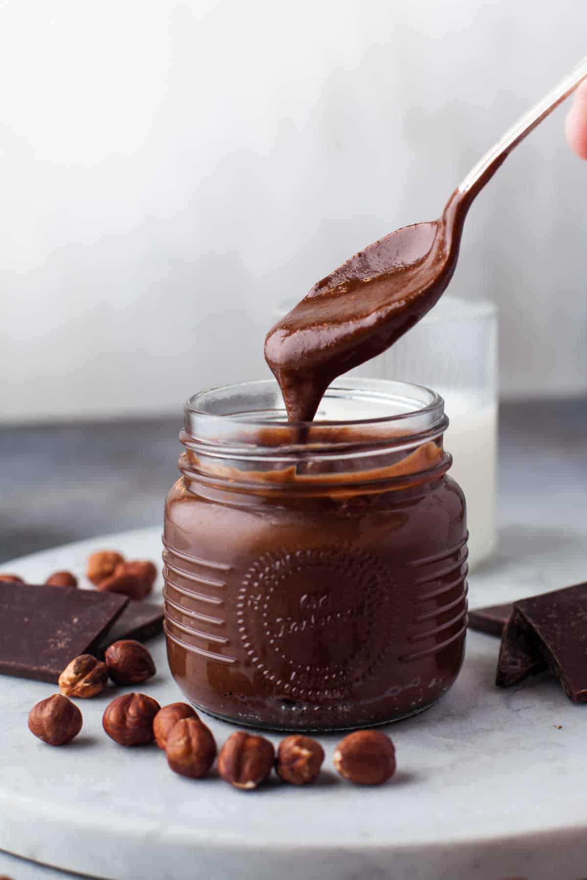 Nutella on a spoon over a jar.