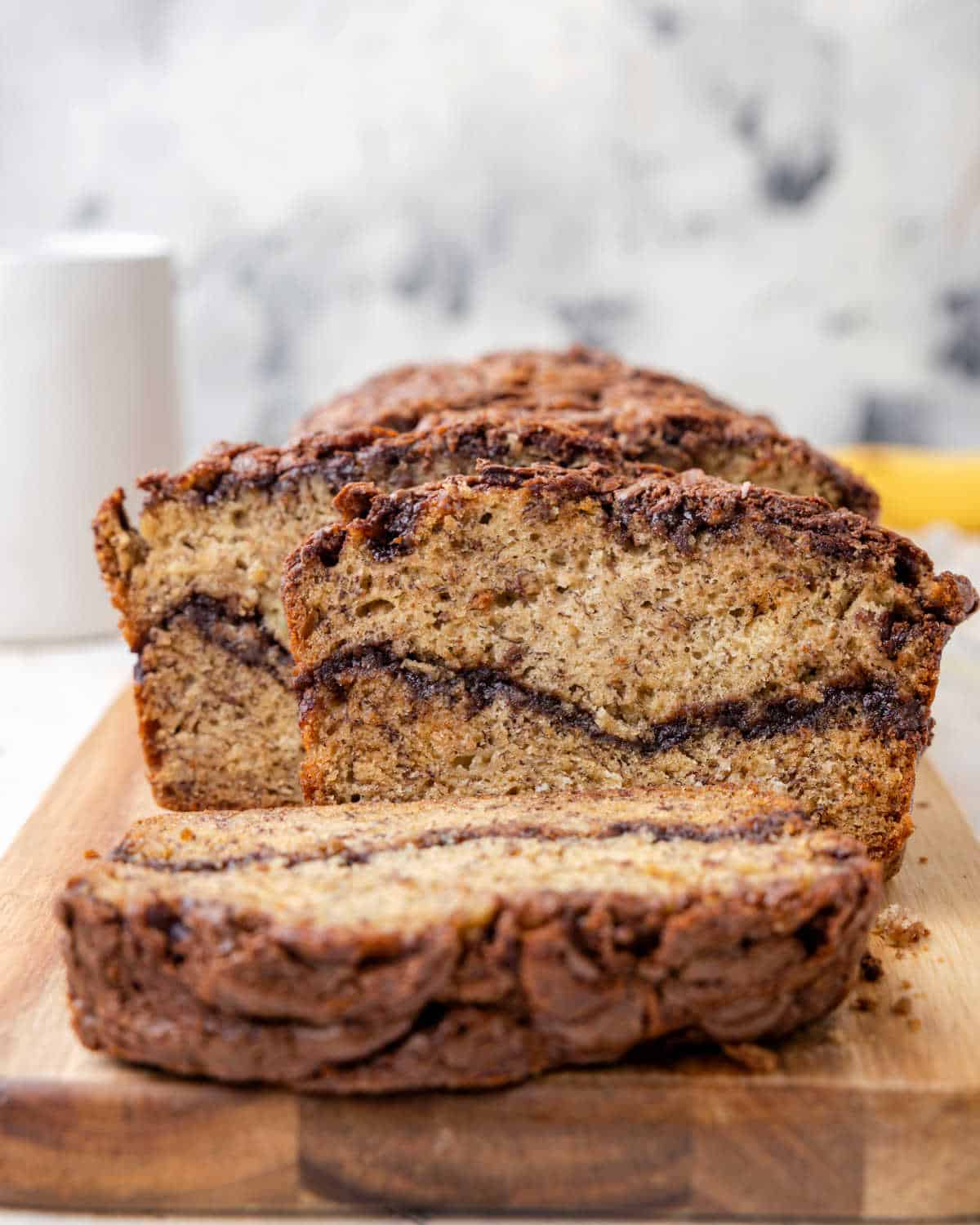 A loaf of Nutella banana bread on a cutting board with a slice off the end.