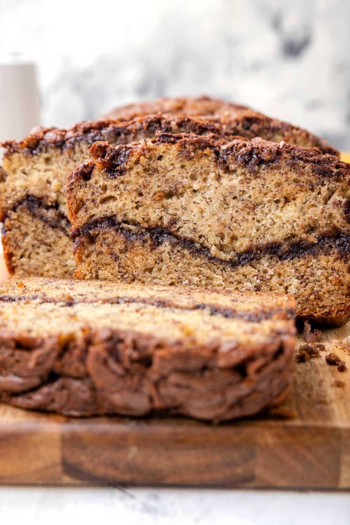 Nutella banana bread loaf on a cutting board with a slice cut off the end.