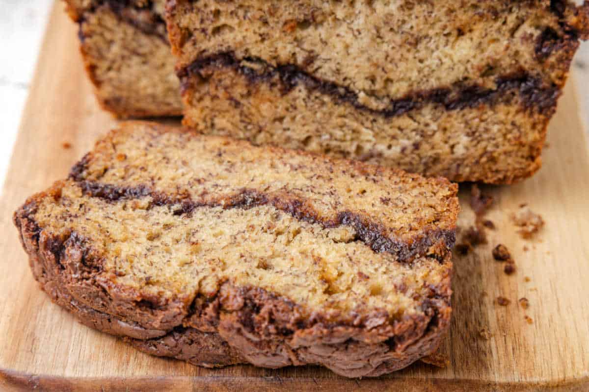 Nutella banana bread on a cutting board with a slice resting on the end.