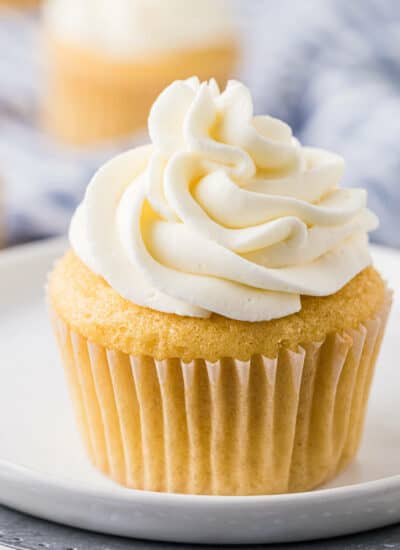 Stabilized whipped cream on top of a vanilla cupcake.