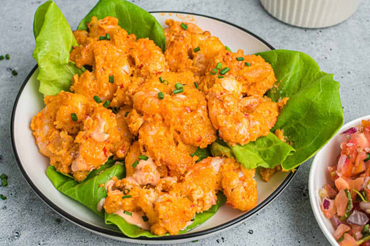 Air fryer bang bang shrimp on a bed of lettuce.