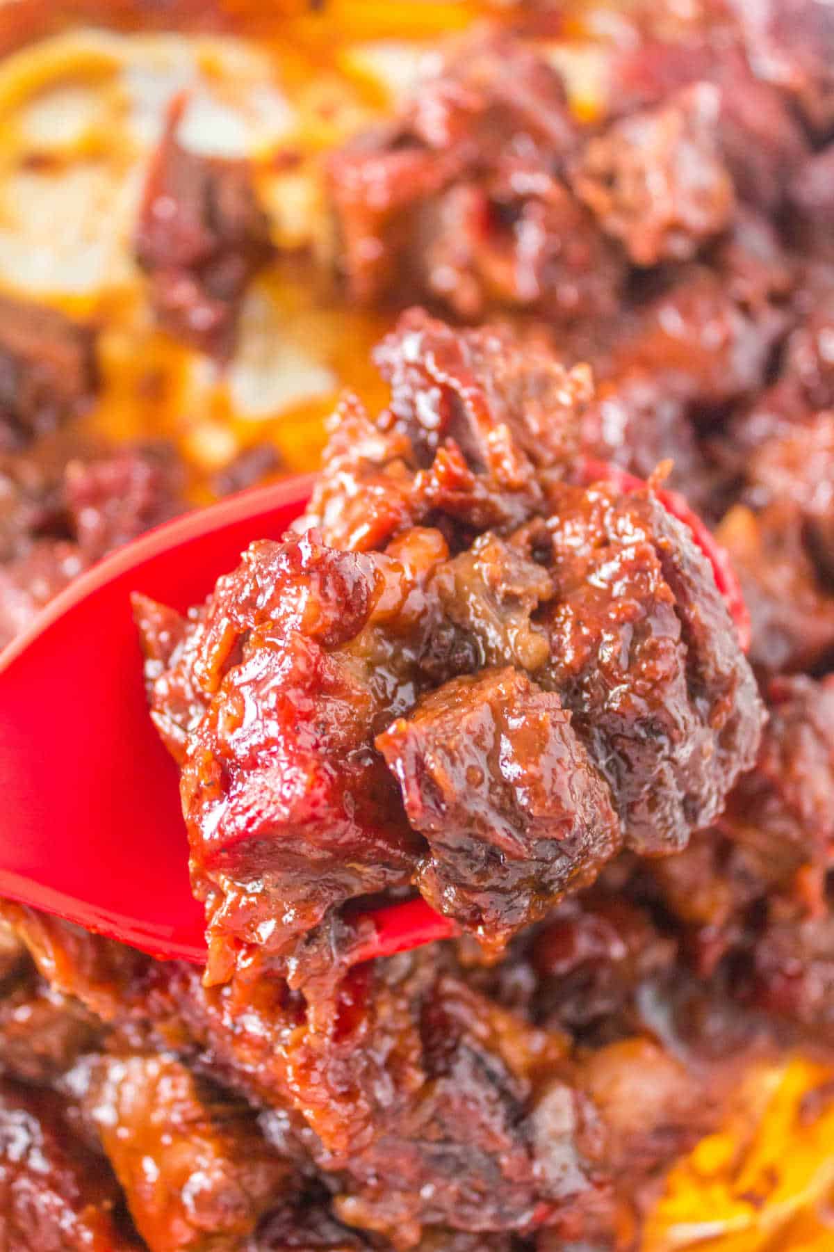 Burnt ends on a red serving spoon.