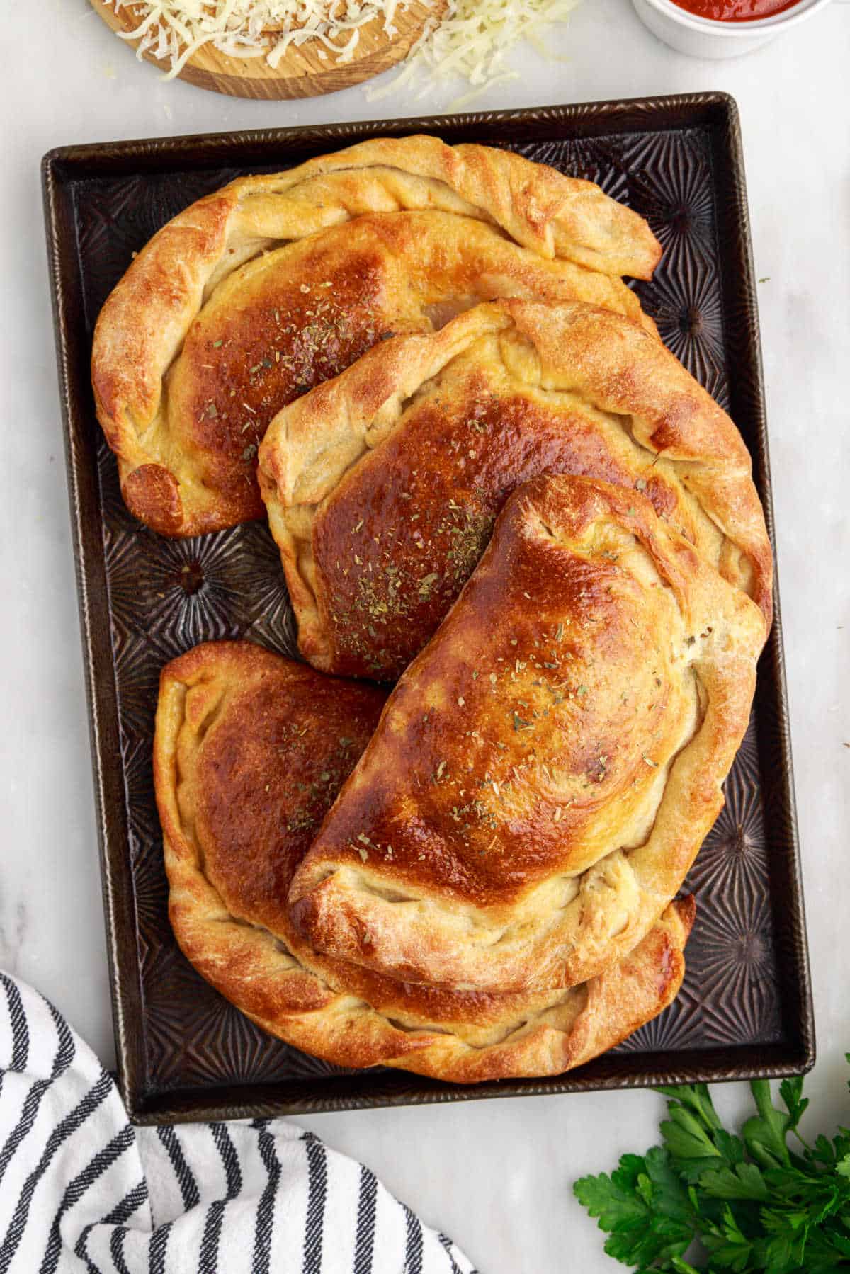 Meat calzones on a baking sheet.