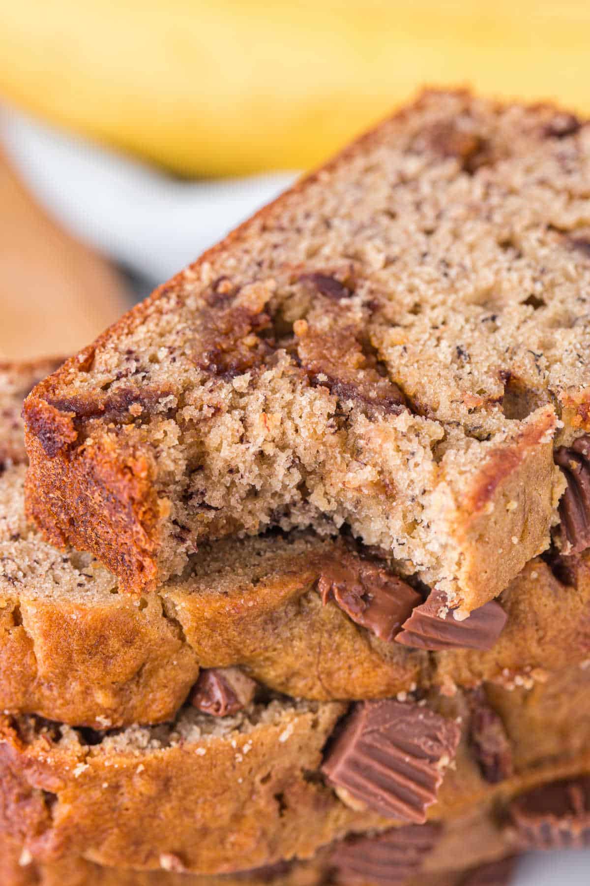 A stack of Reese's Peanut Butter Banana Bread slices with a bite out of the slice at the top.