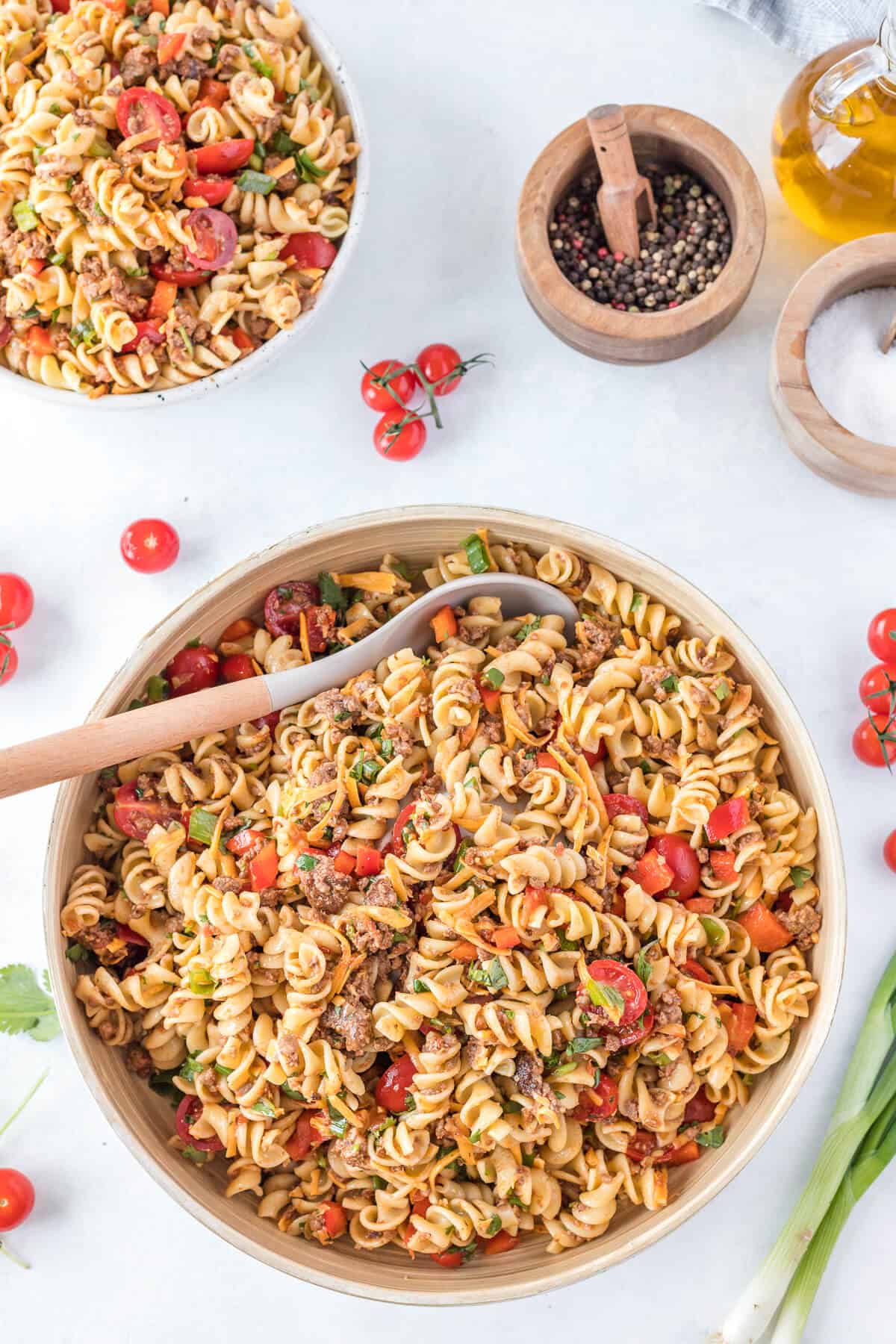 A bowl of taco pasta salad with a serving spoon.