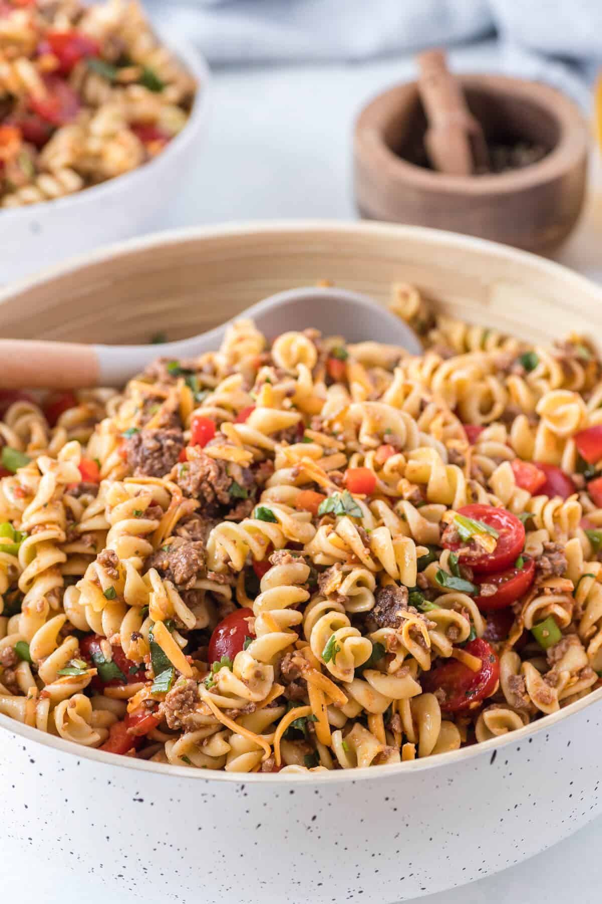 A bowl of taco pasta salad with a serving spoon.