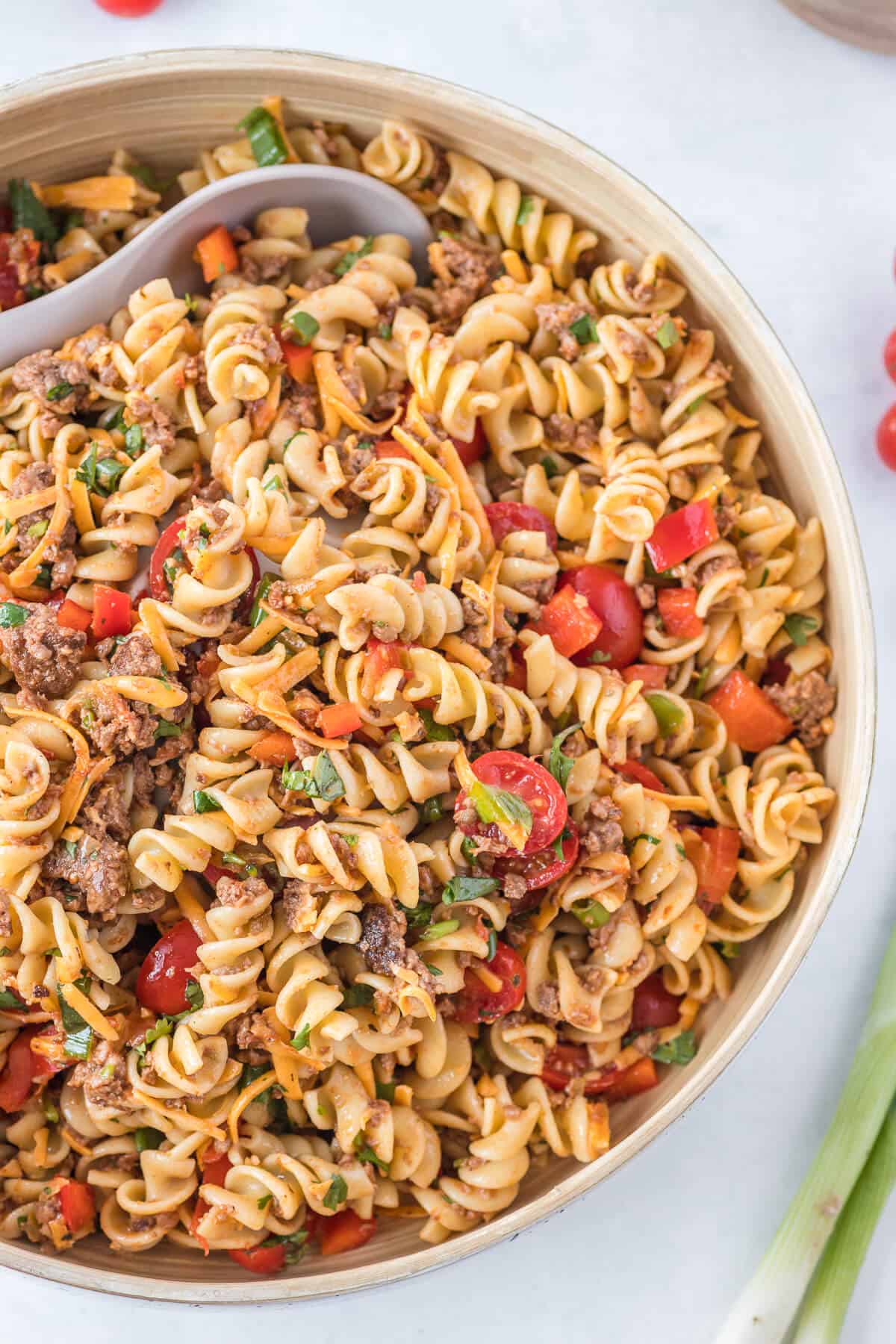A bowl of taco pasta salad with a serving spoon.