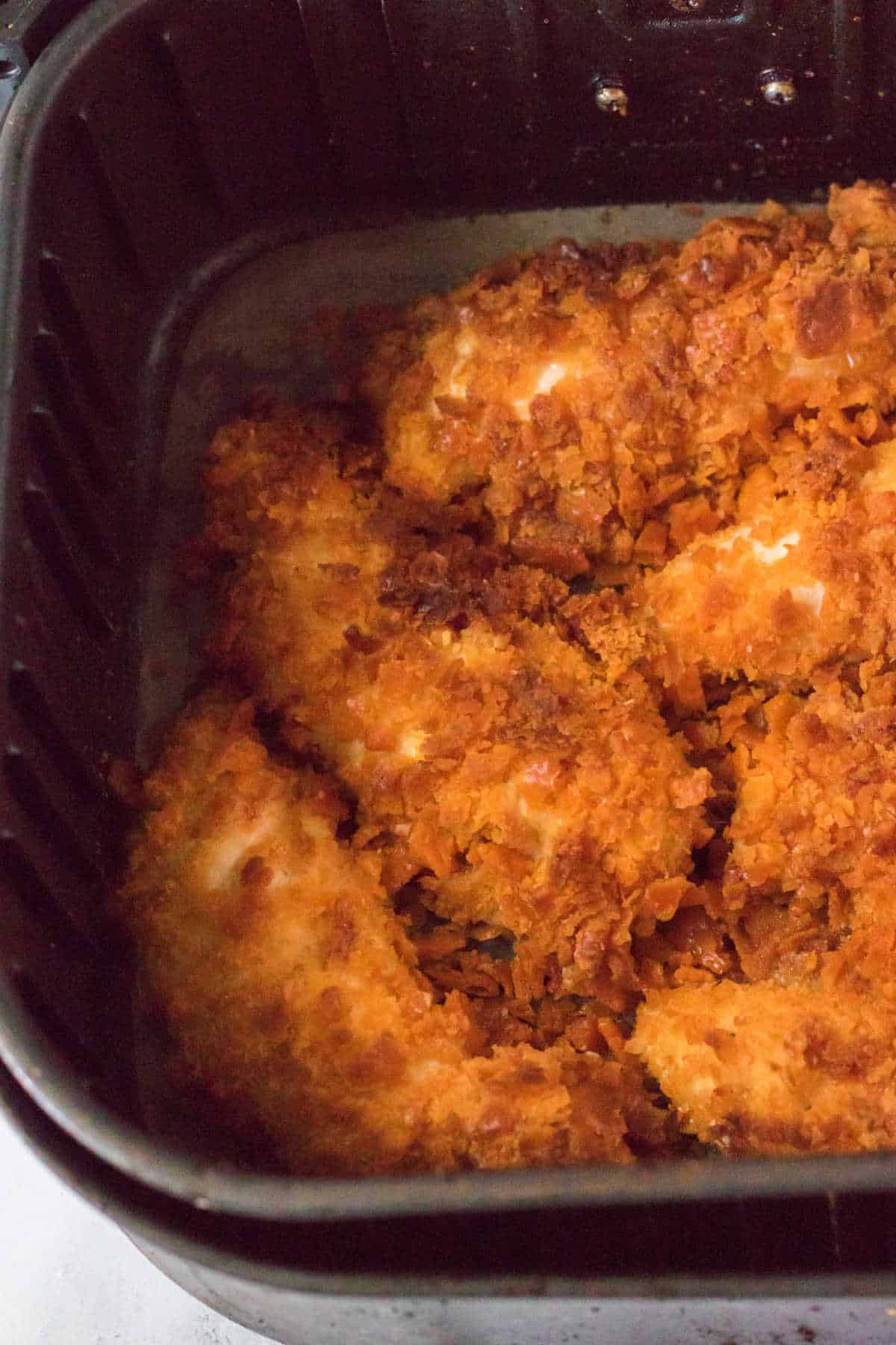 Cheez it chicken tenders in an air fryer basket.