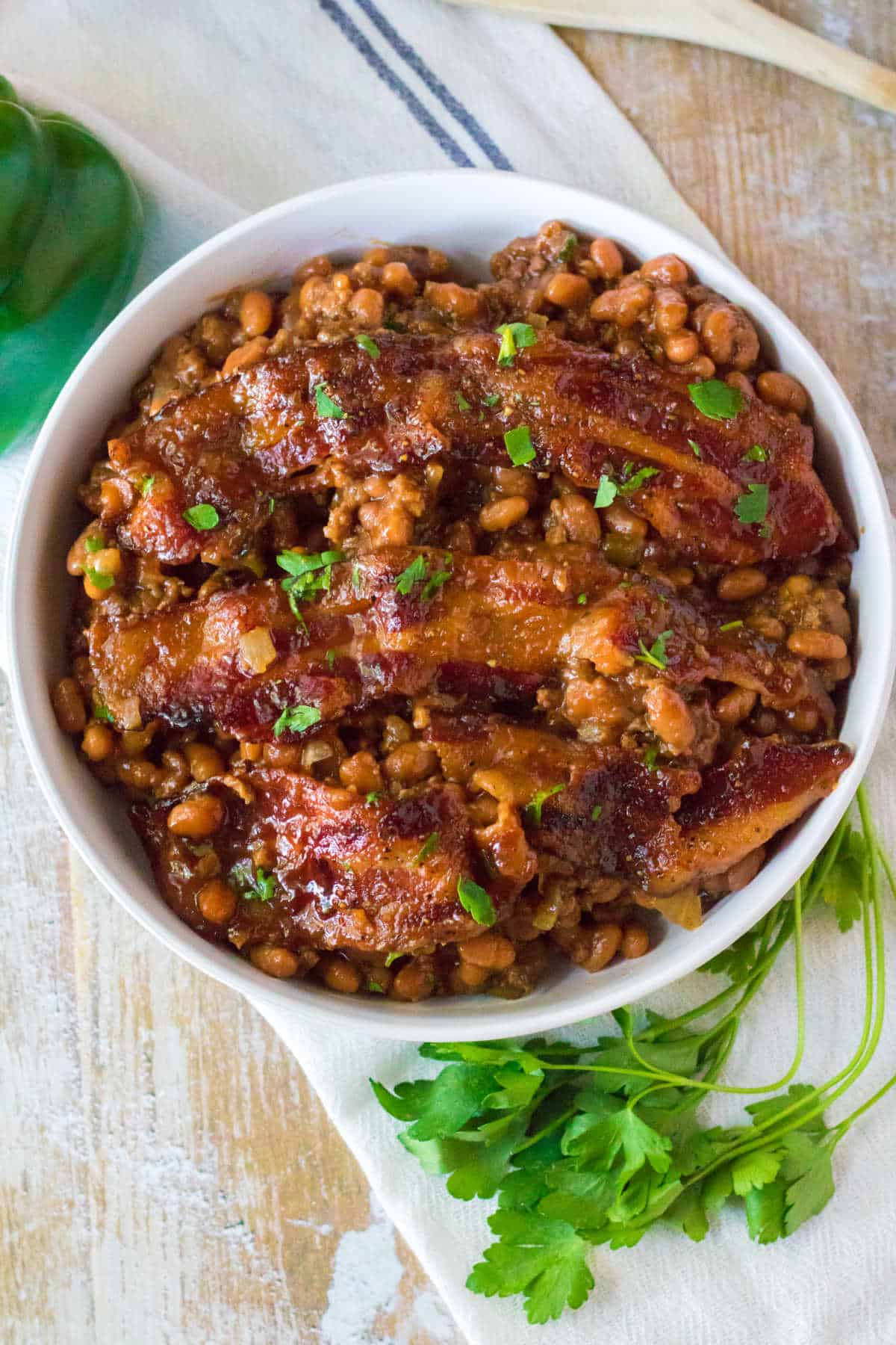 Baked beans with ground beef in a white bowl.