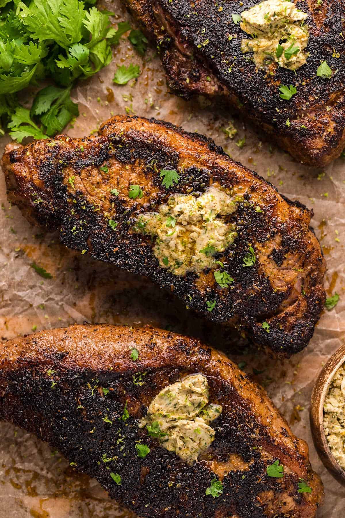 Blackened steaks on a piece of parchment paper.