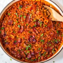 The beans in a skillet with a wooden spoon.