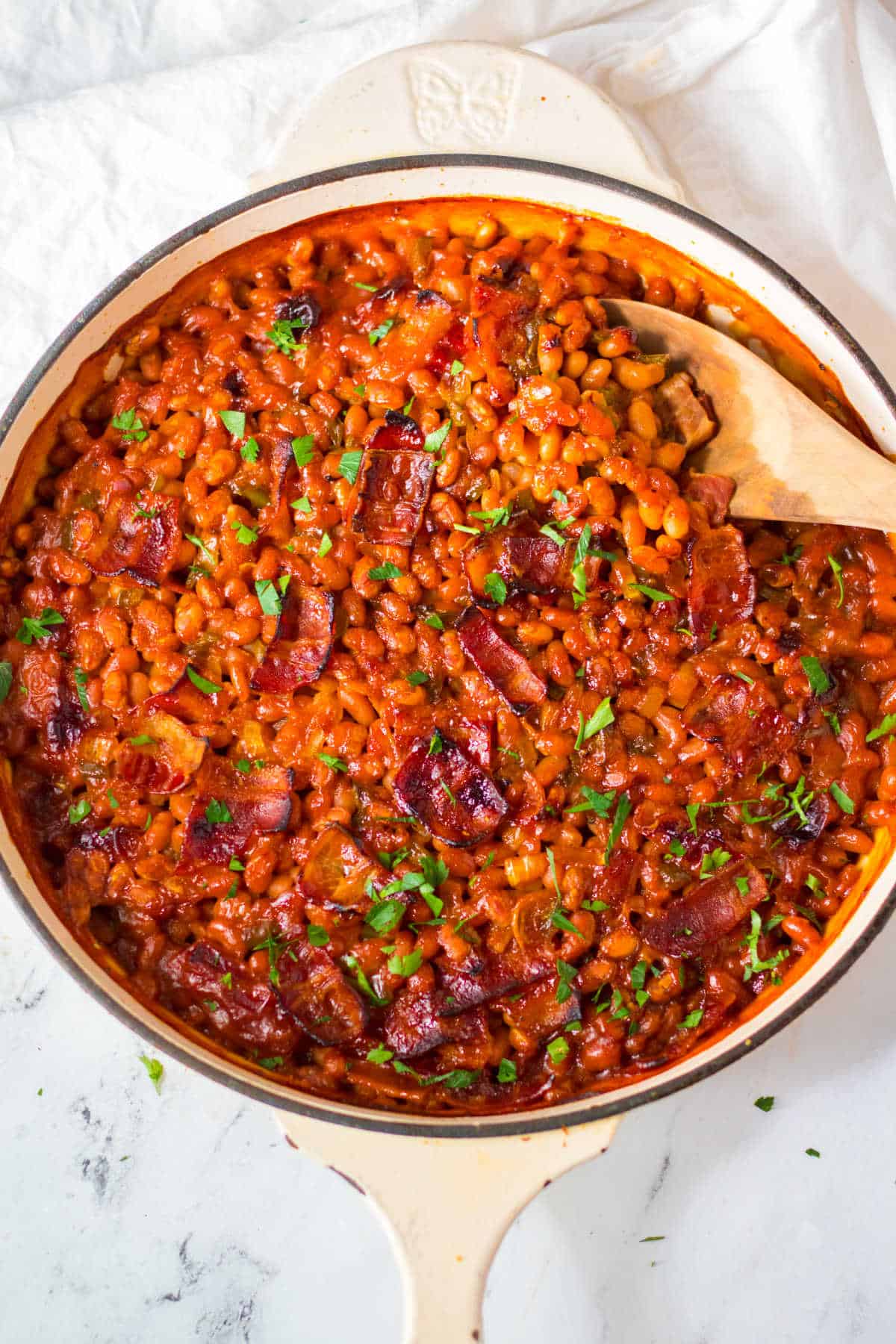Skillet of Dr Pepper Baked Beans with a wooden spoon.