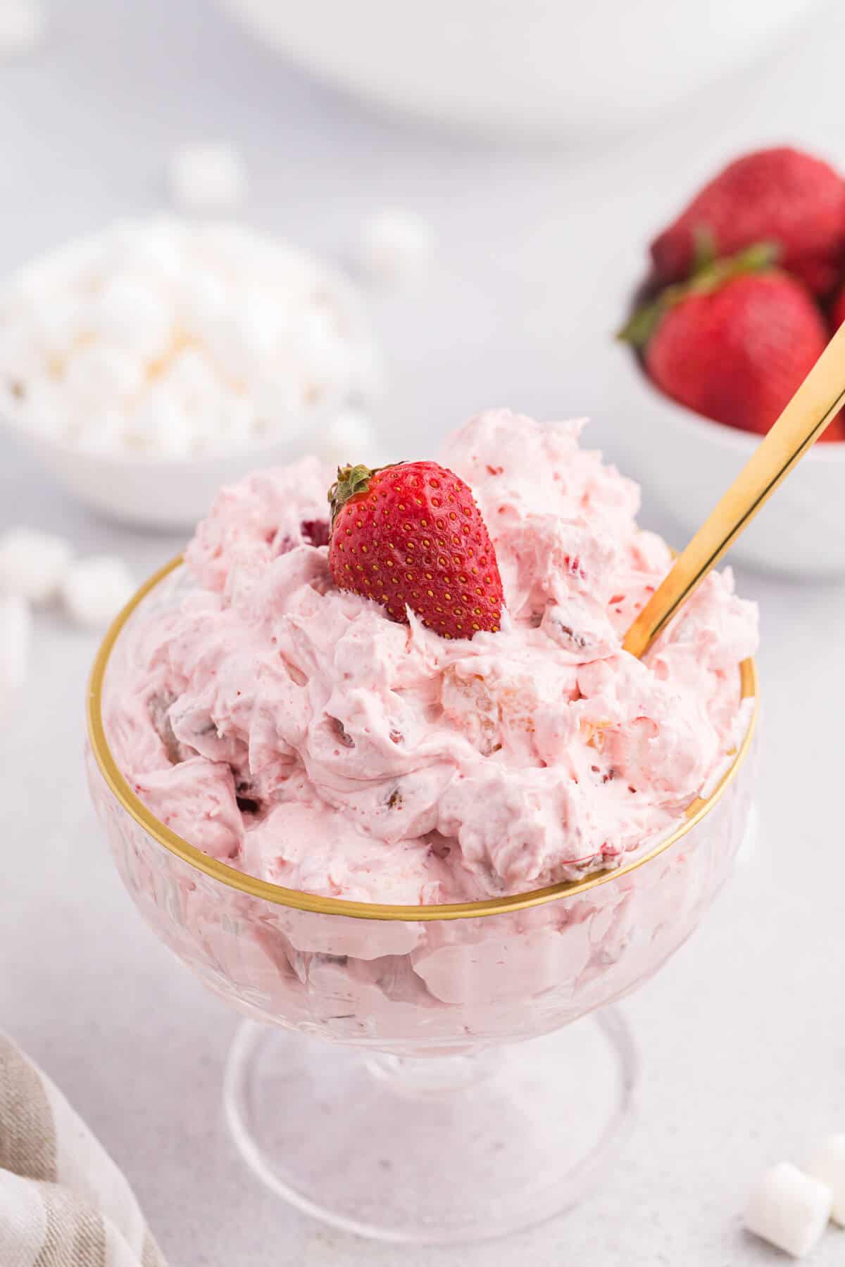 Strawberry fluff salad in a parfait dish with a spoon.