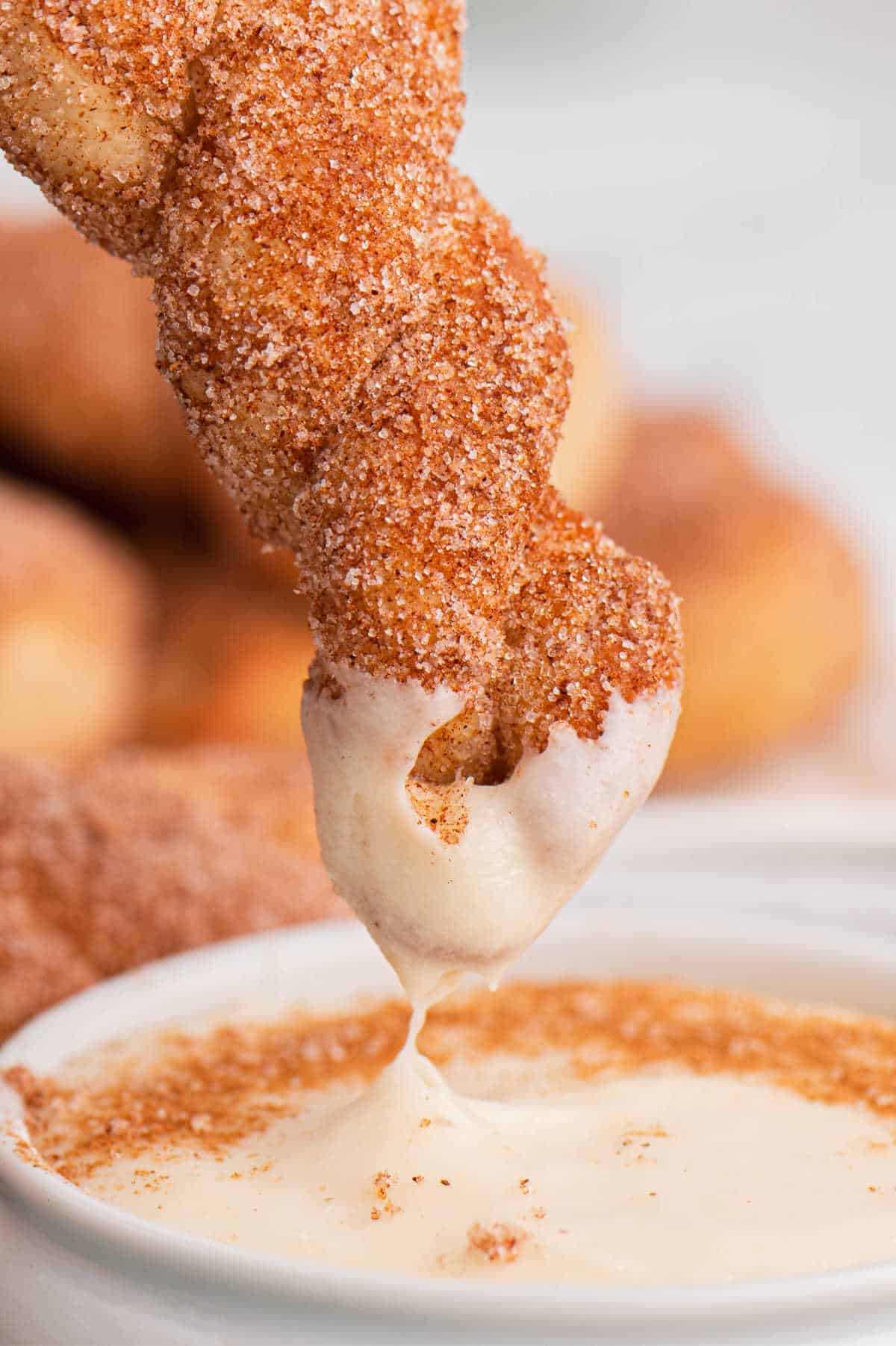 Air fryer cinnamon twist dipped in cream cheese dip.