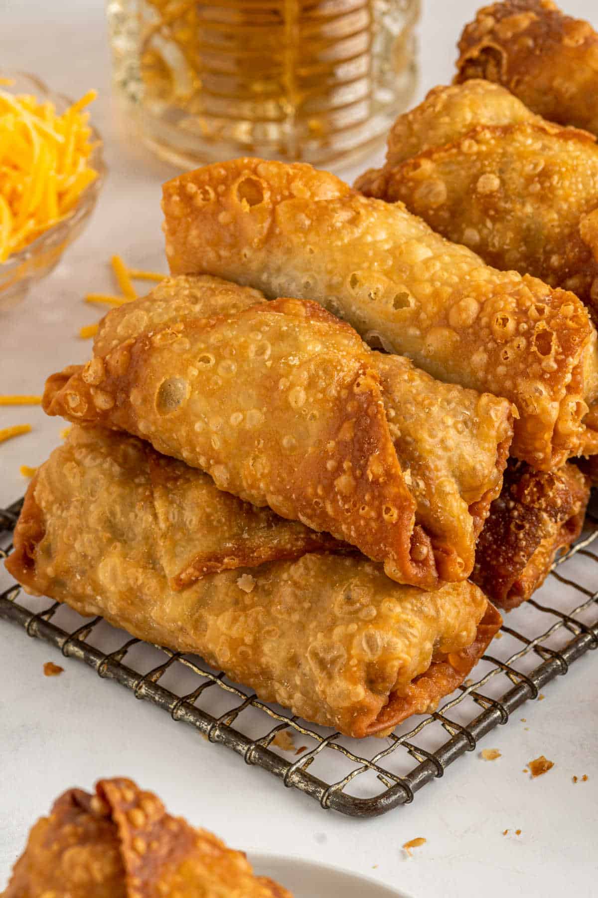 Cheeseburger egg rolls stacked on a wire rack.