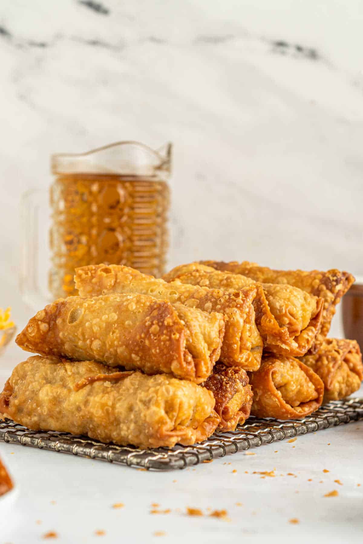 Cheeseburger egg rolls stacked on a wire rack.