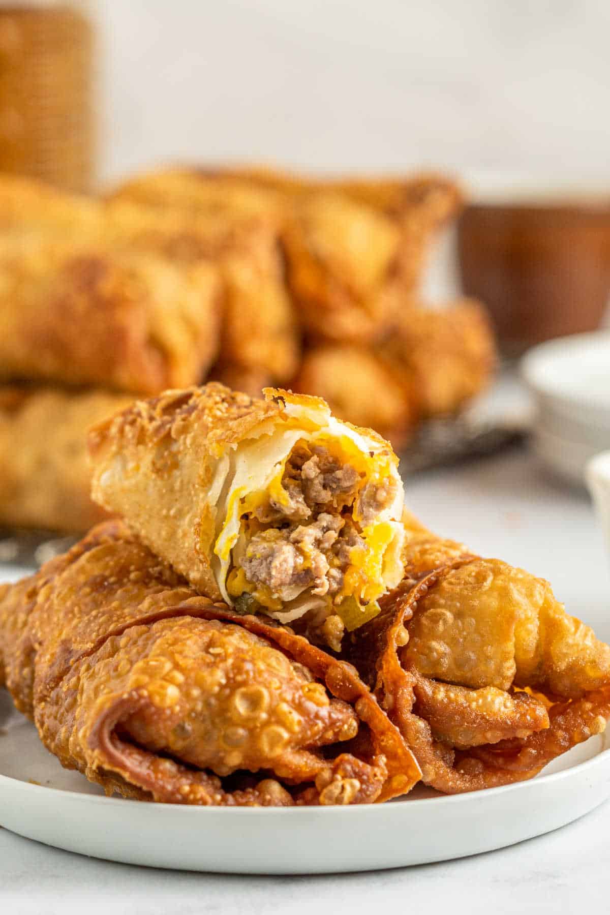 Cheeseburger egg rolls on a plate with a bite out of the top egg roll.