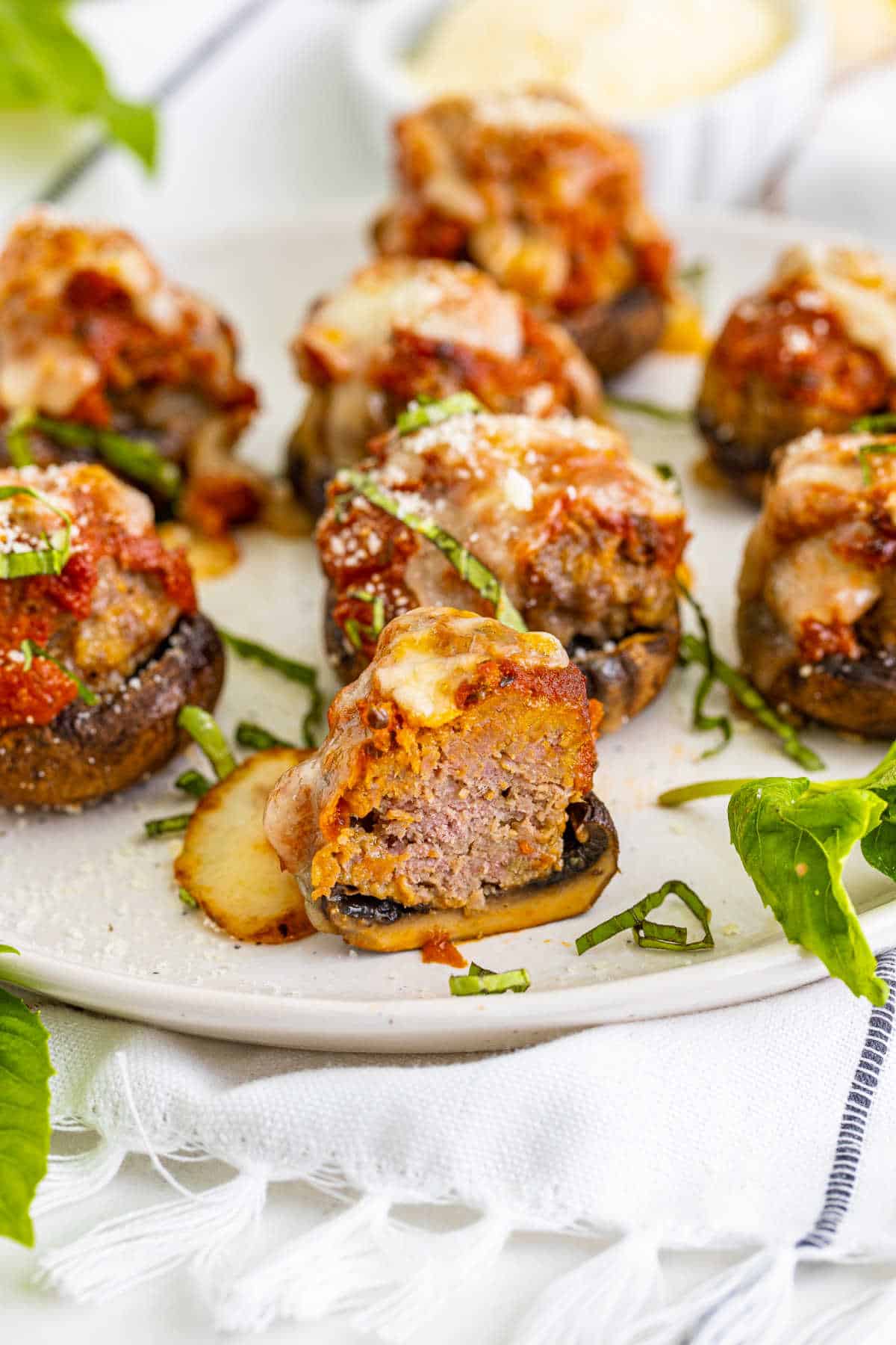 A meatball stuffed mushroom on a plate that's been cut in half.