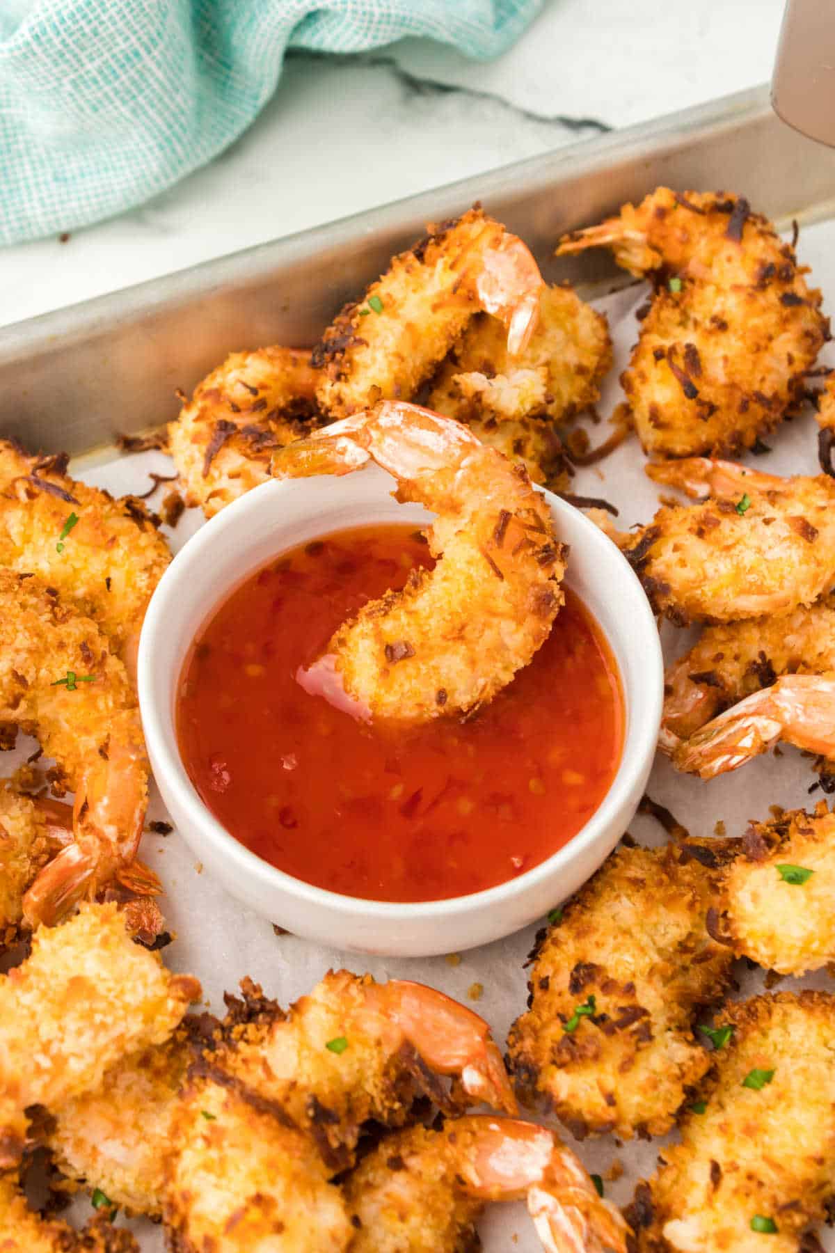 A coconut shrimp in a bowl of dipping sauce.