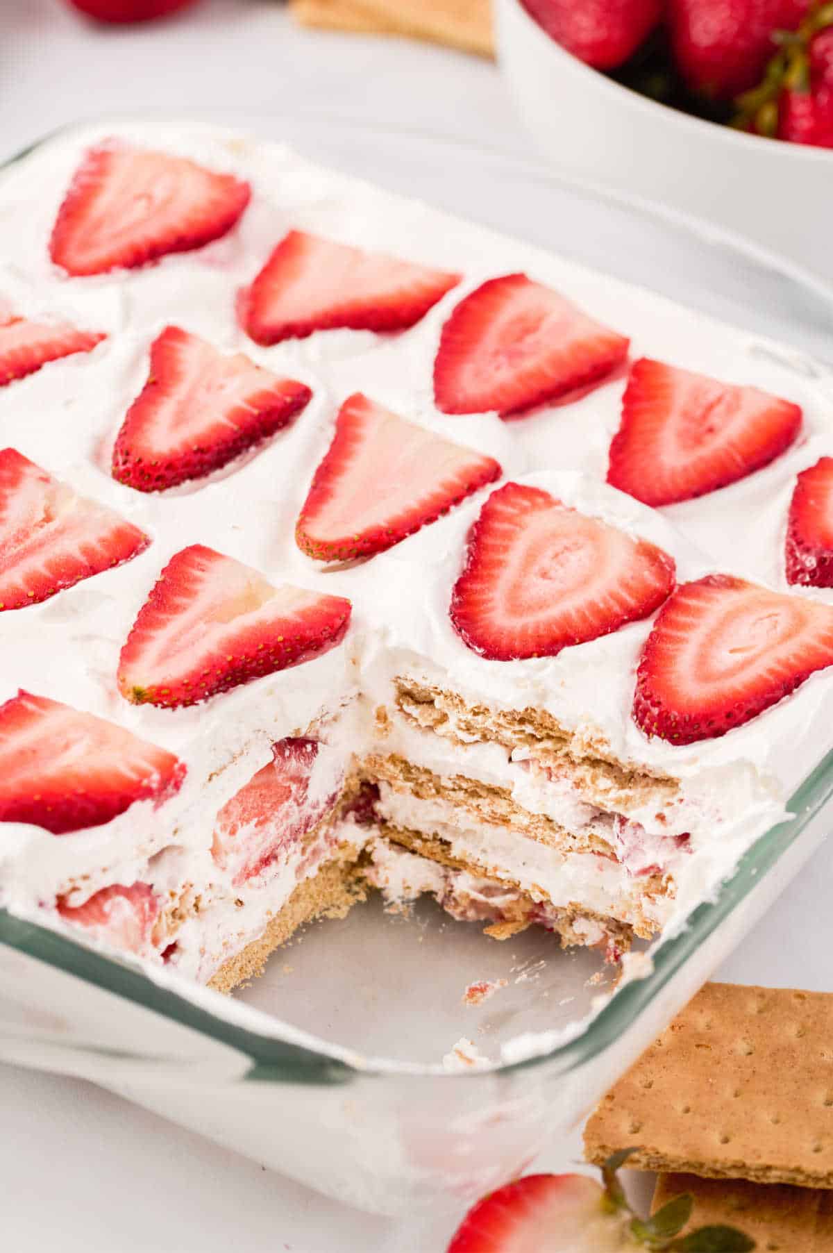 A pan of strawberry icebox cake with a piece cut out.