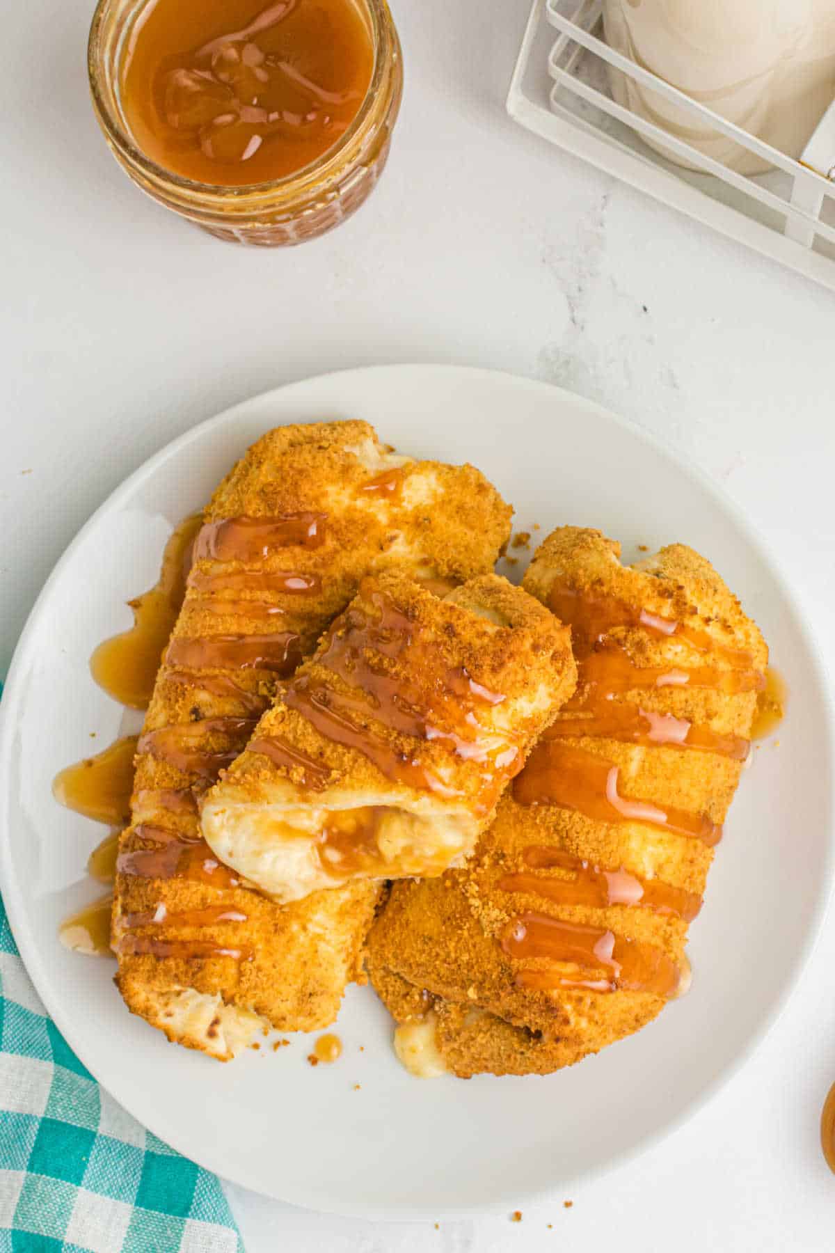 A plate of air fryer caramel cheesecake chimichangas on a plate with a bite out of the top one.