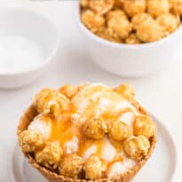 Caramel crunch ice cream sundae in a waffle bowl on a plate.