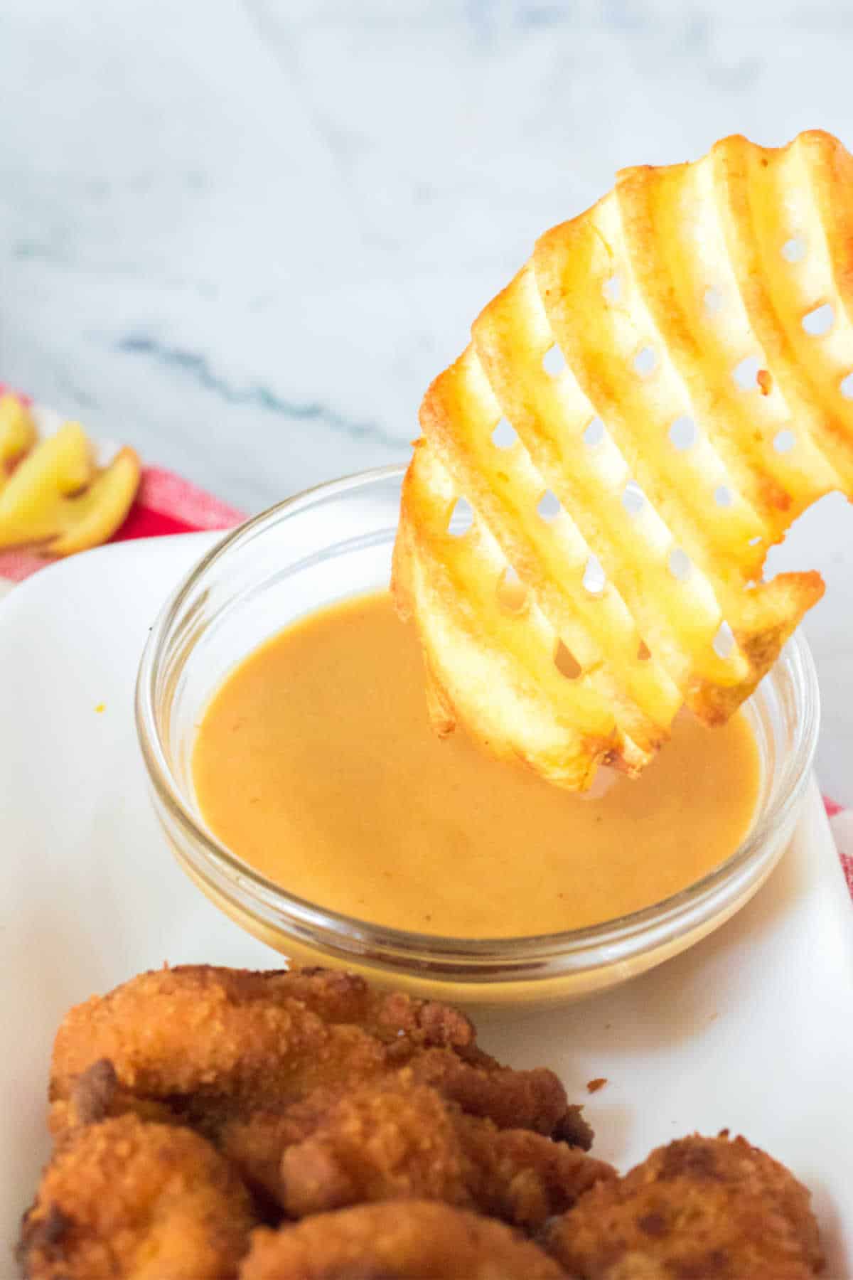 A waffle fry being dipped in sauce.