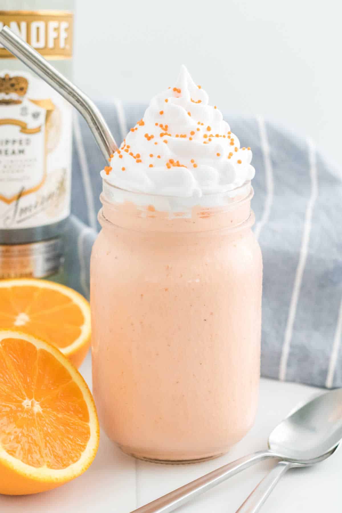 A boozy orange creamsicle milkshake with a metal straw.