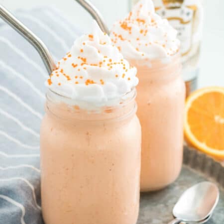 Two milkshakes with metal straws.