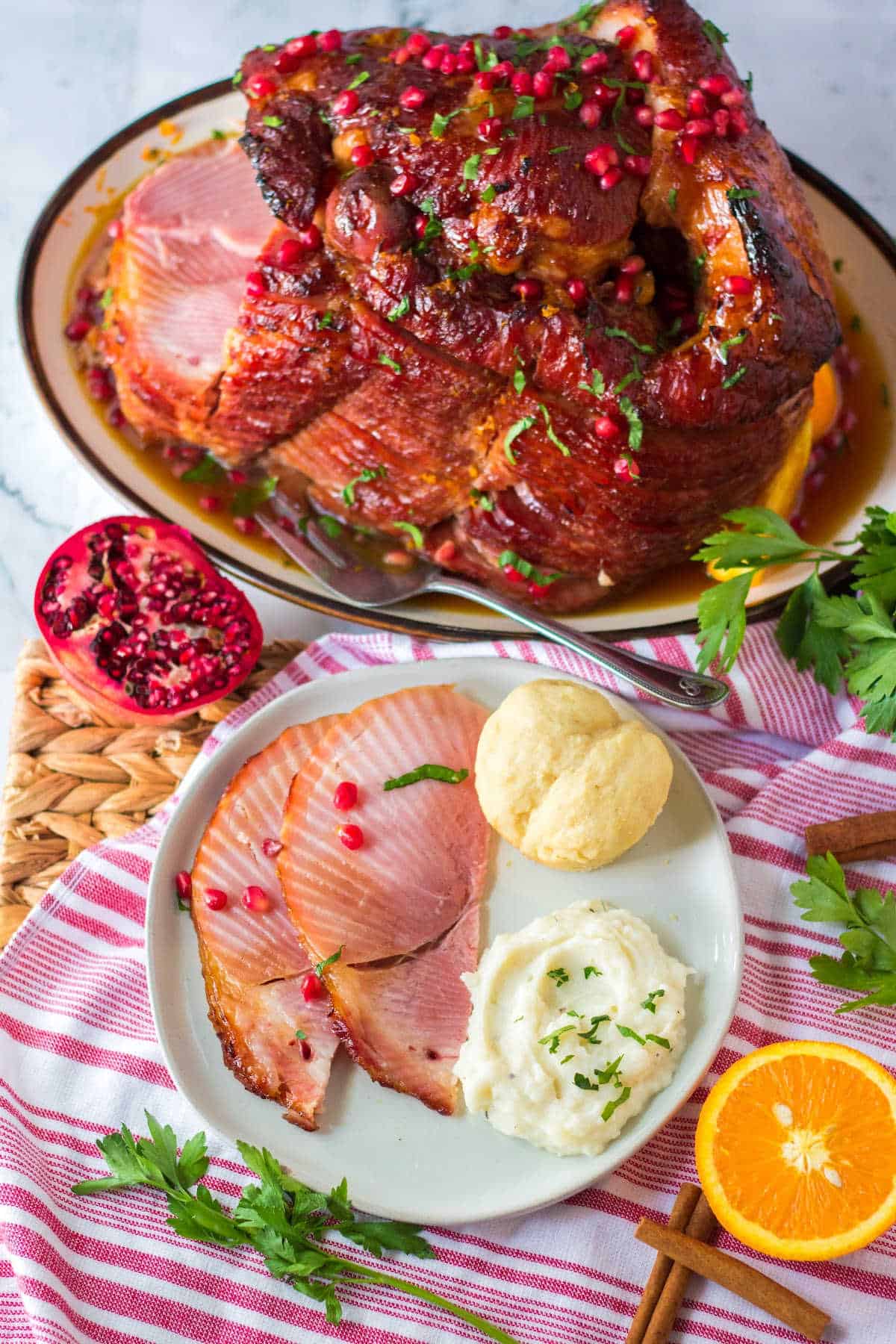 Christmas ham served with other sides and the whole ham in the background.