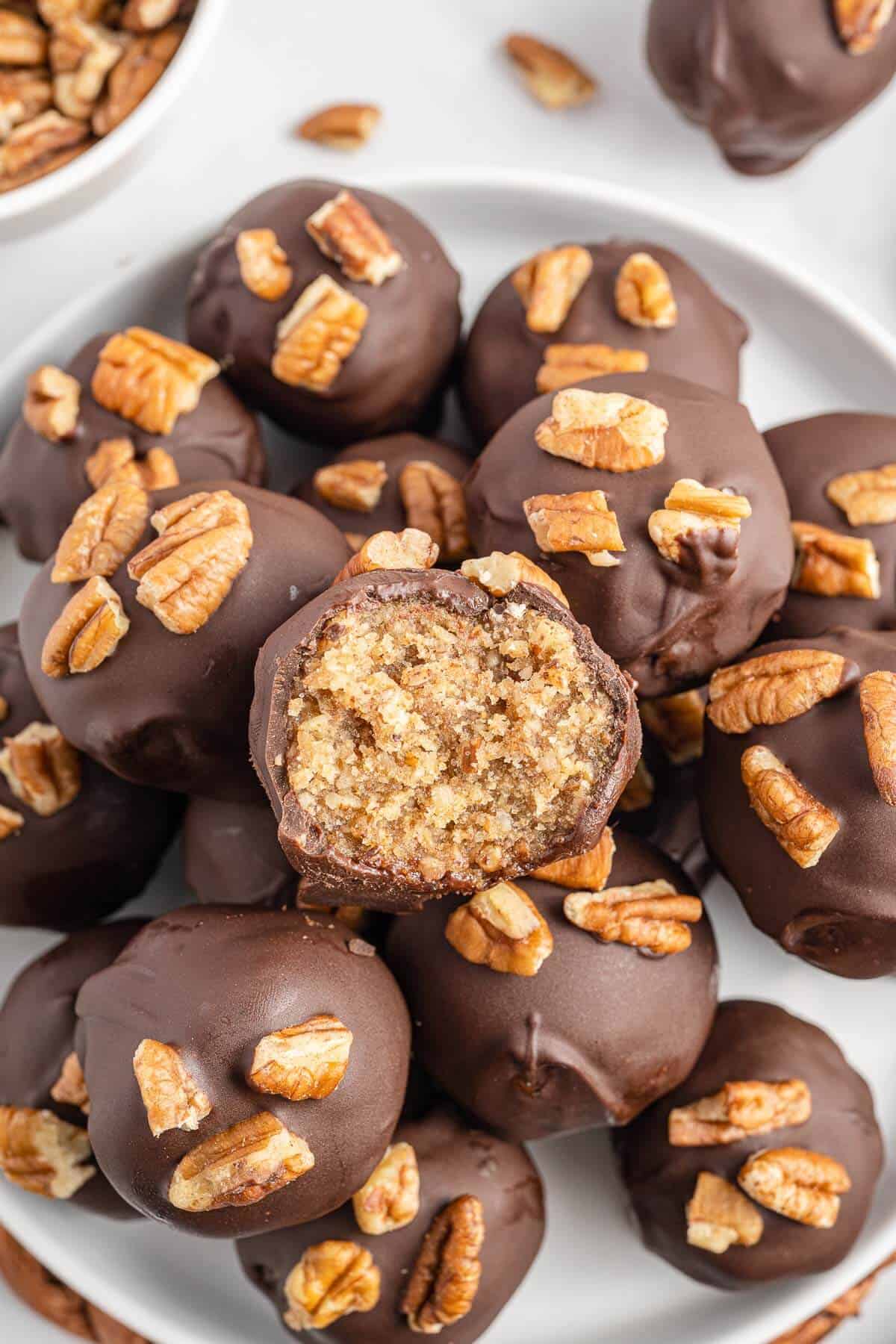 Pecan pie balls on a plate with a bite out of the top ball.