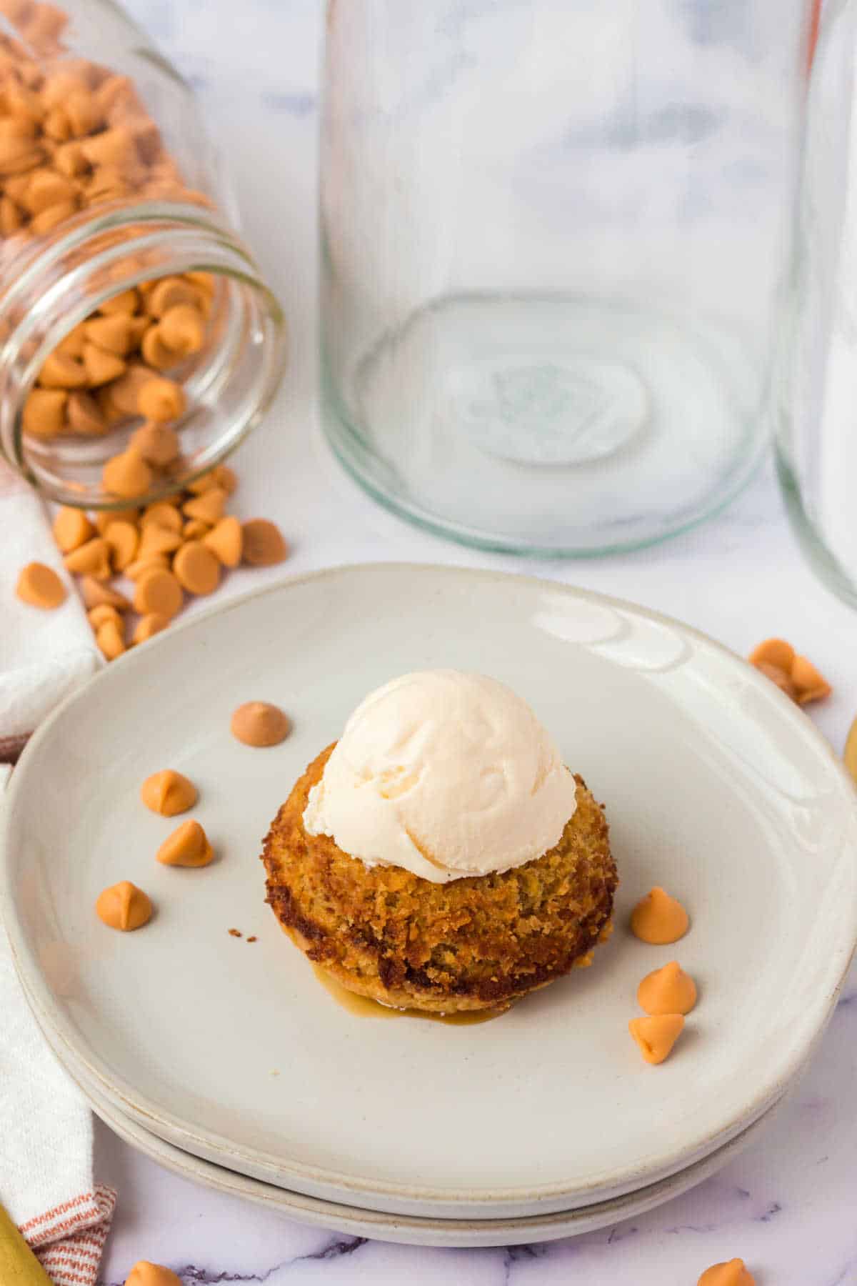 A butterscotch lava cake on a plate topped with a scoop of vanilla ice cream. 