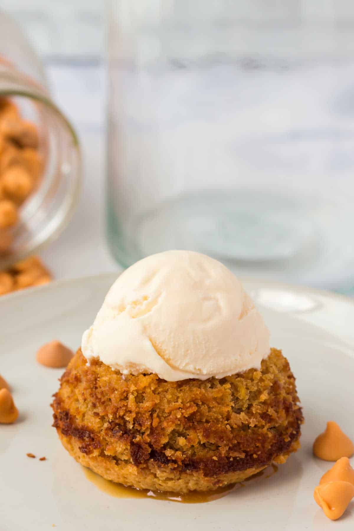 A butterscotch lava cake on a plate topped with vanilla ice cream.