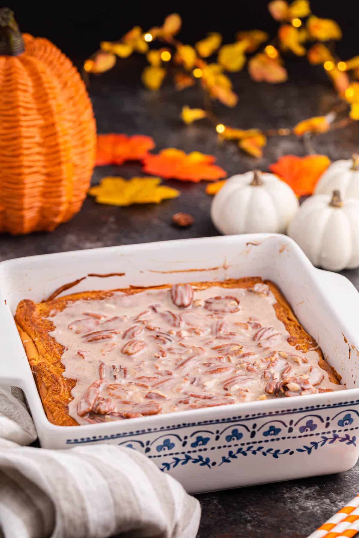 A white pan of pumpkin cream cheese danish bake surrounded by fall decor.