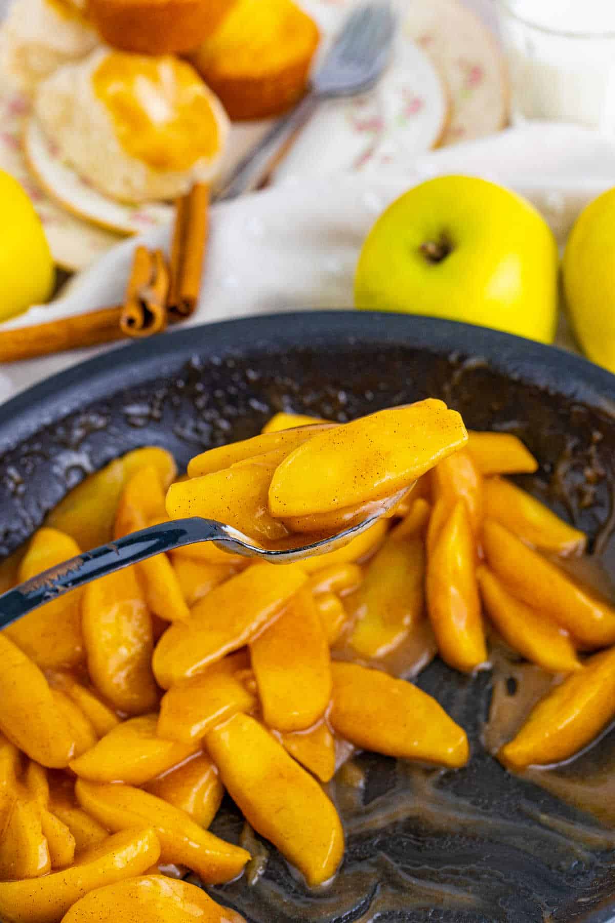 Fried apples in a skillet with a serving spoon.