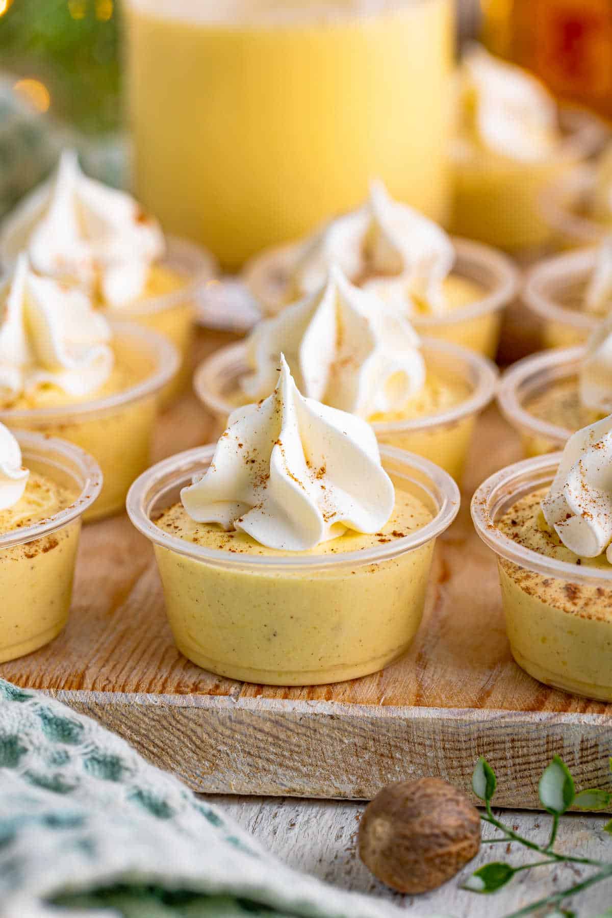 Eggnog pudding shots on a wooden board.