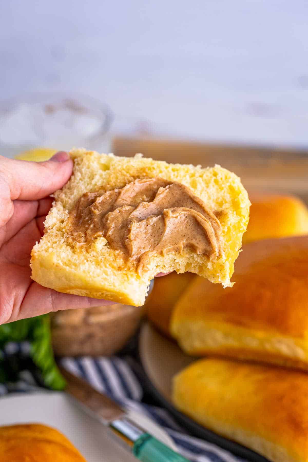 A hand holding a sliced roll topped with cinnamon butter.