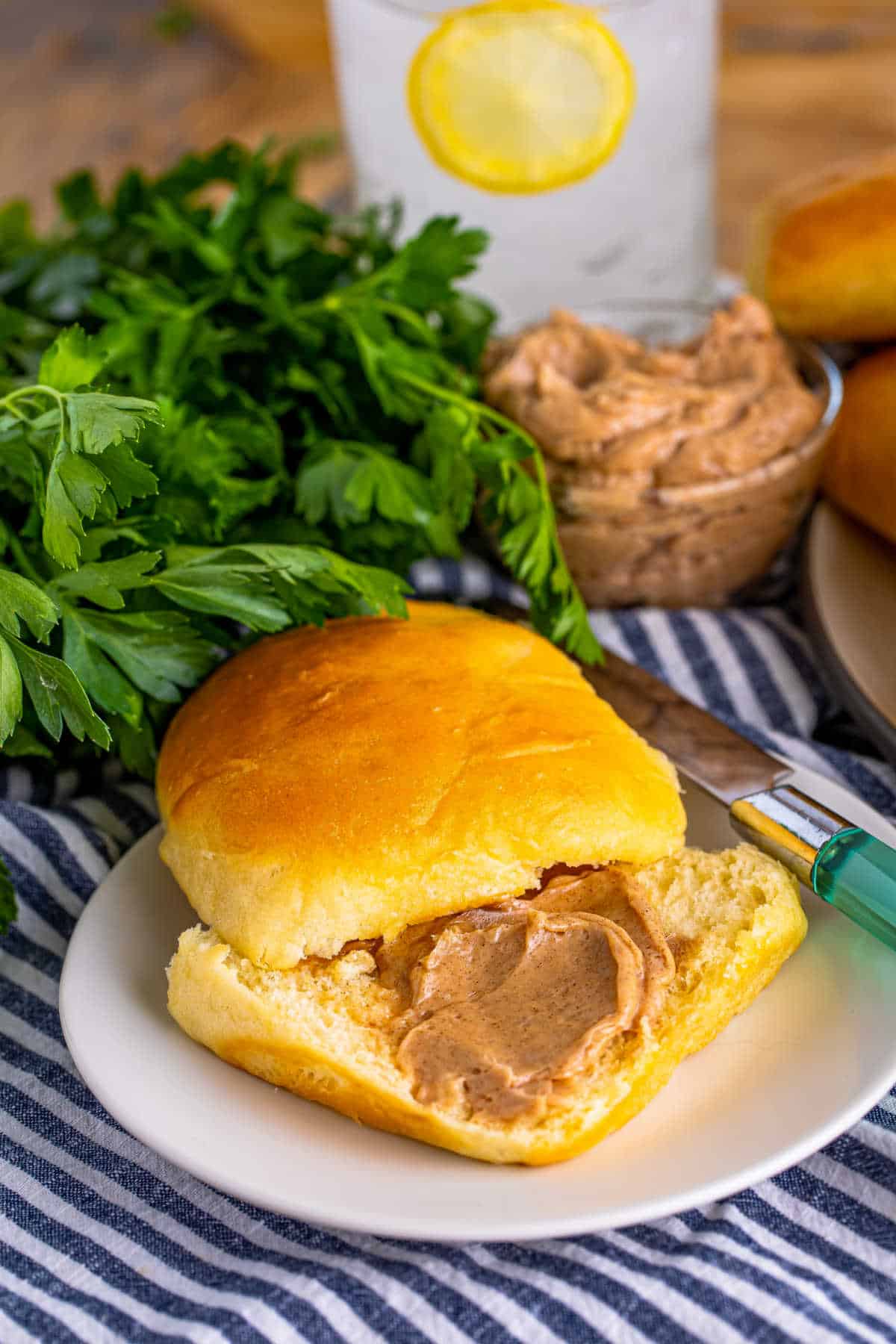 A sliced Texas Roadhouse Roll with cinnamon butter on a plate.