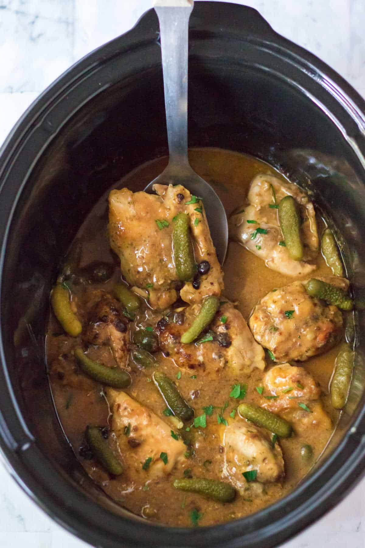 Pickle chicken in a crockpot with a serving spoon.