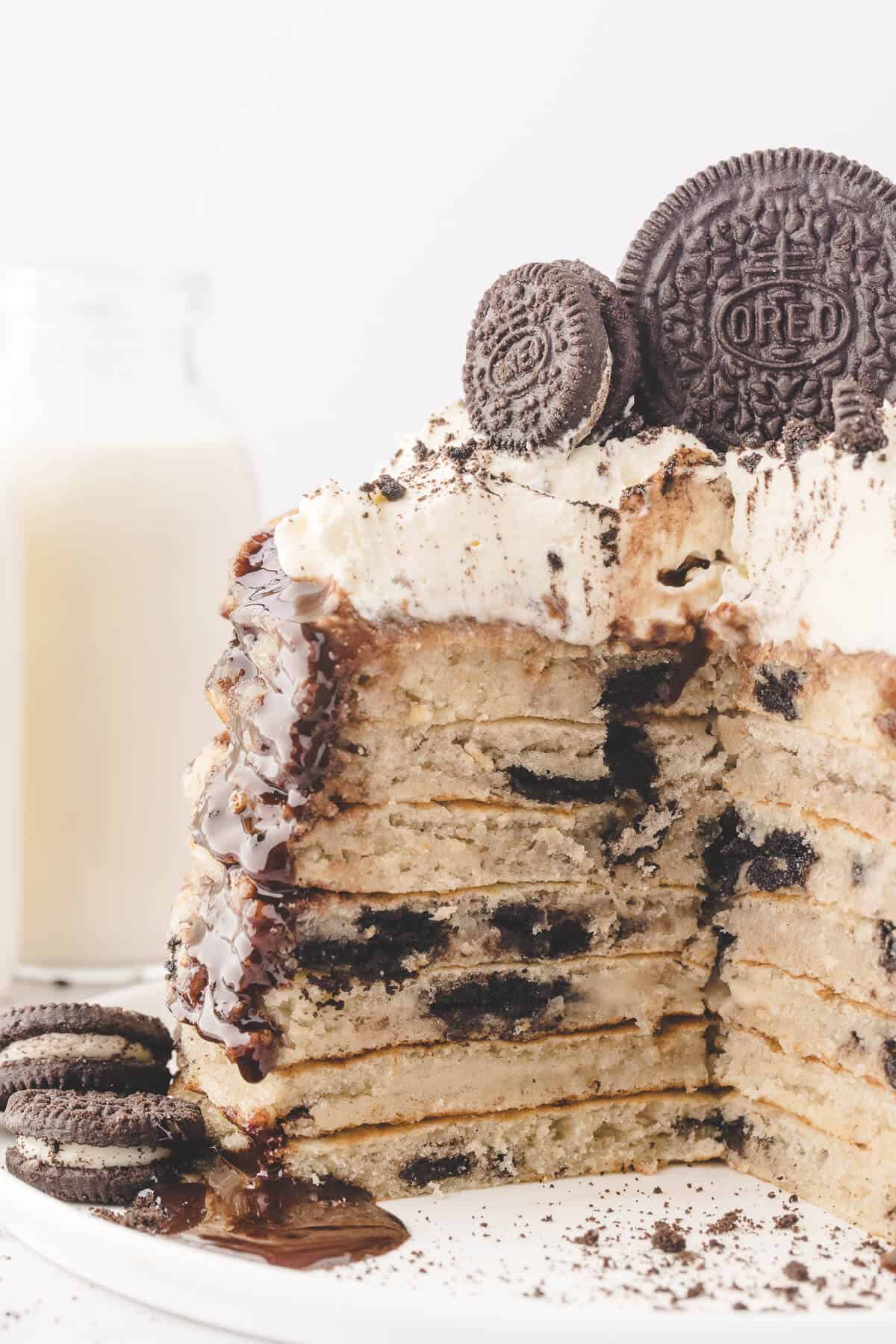A stack of Oreo pancakes with a big piece cut out of it.